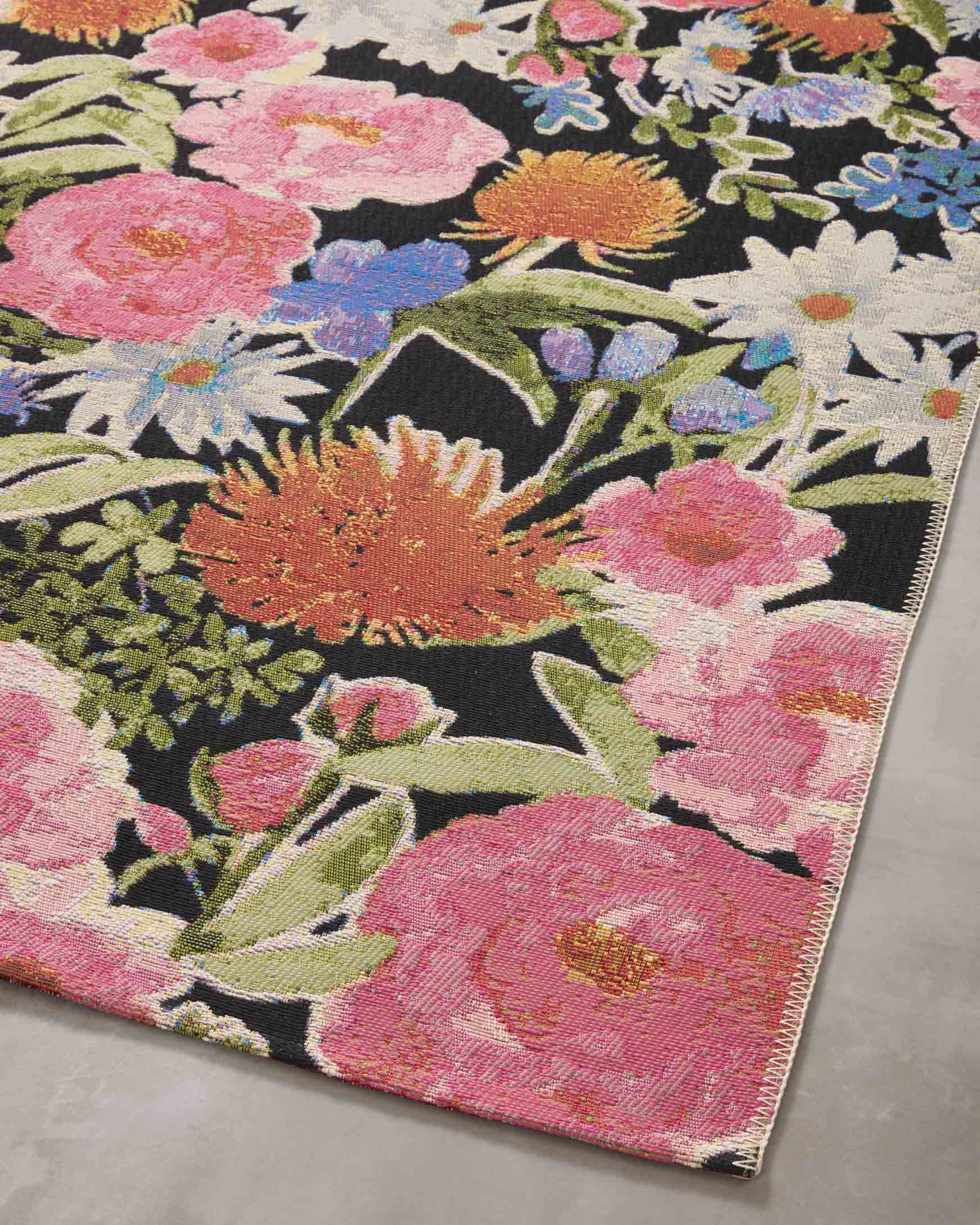 Floral botanical rug corner view with multicolor flowers on a dark background and border trim.