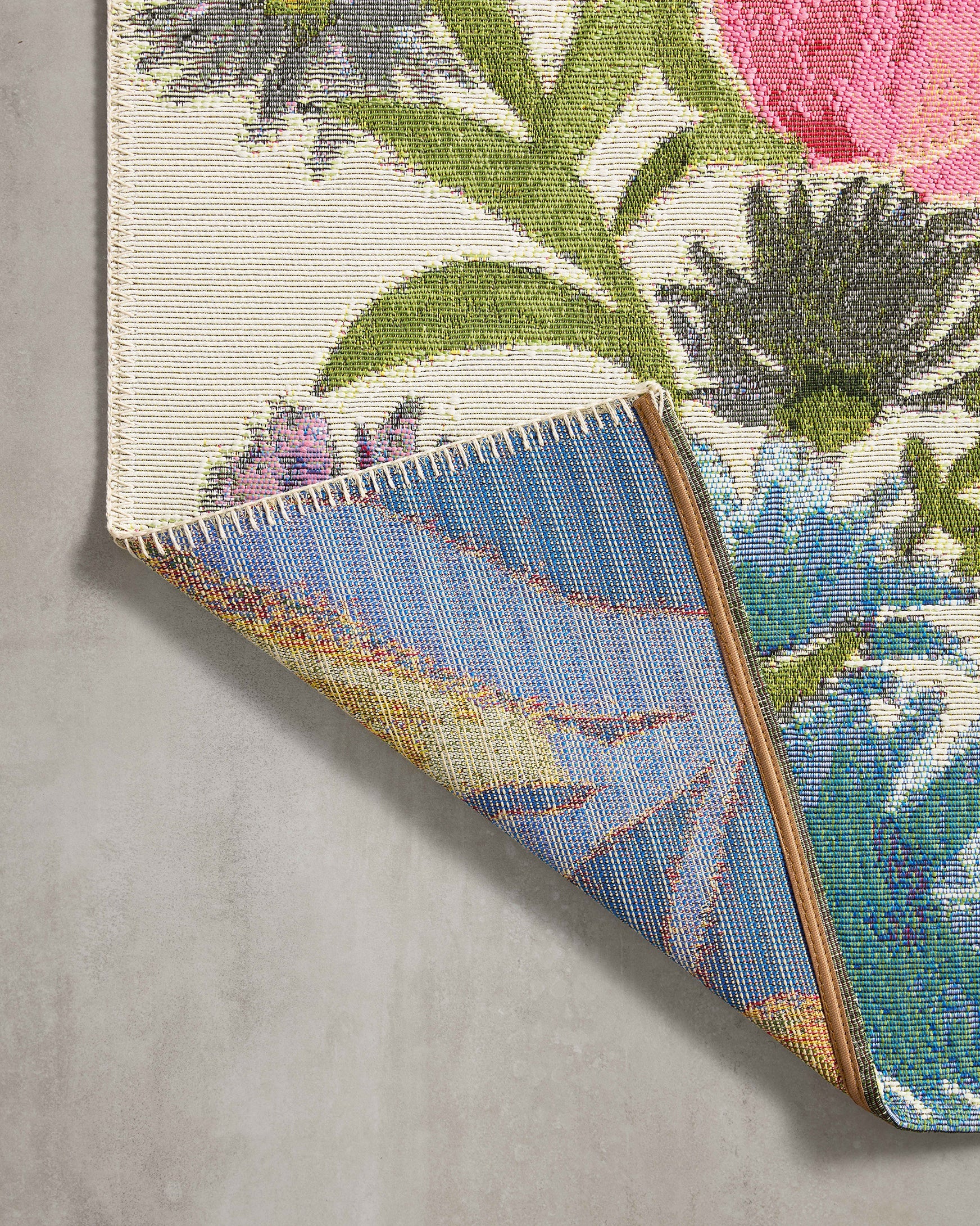 Rug corner detail with fringed woven edge and multicolor floral pattern