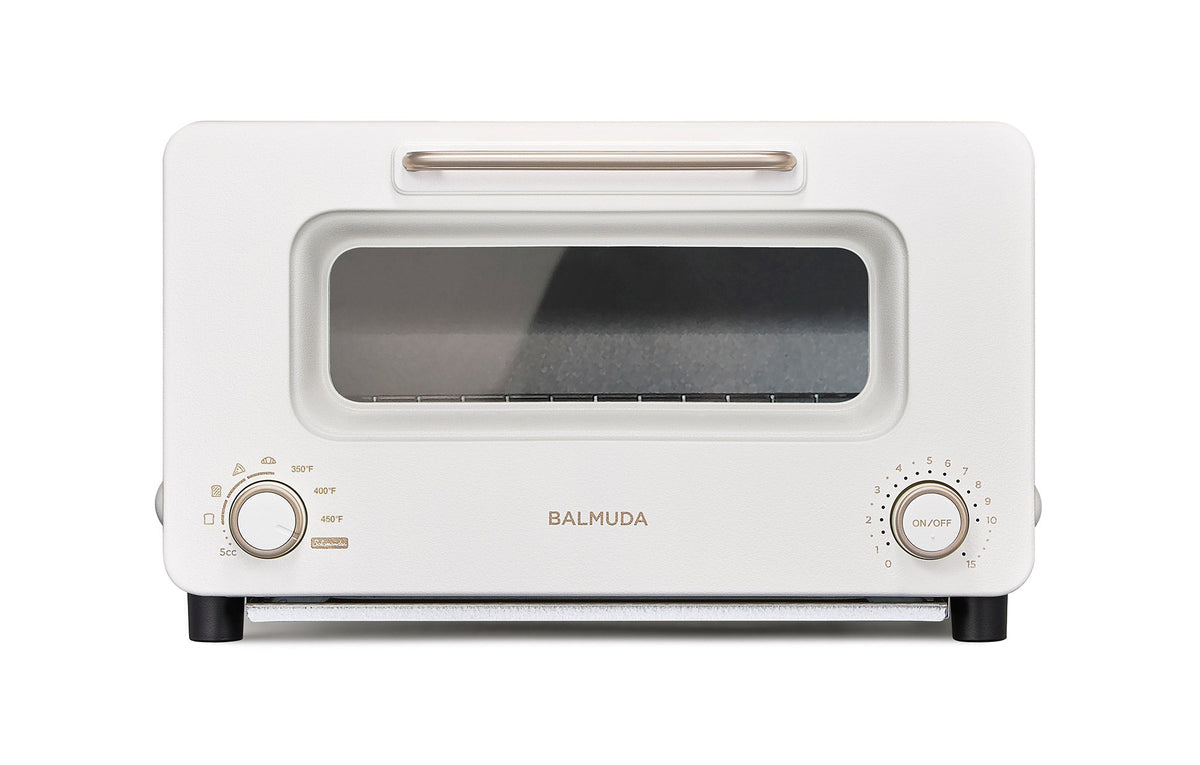 Off-white countertop toaster oven with glass door, front dials, and BALMUDA logo