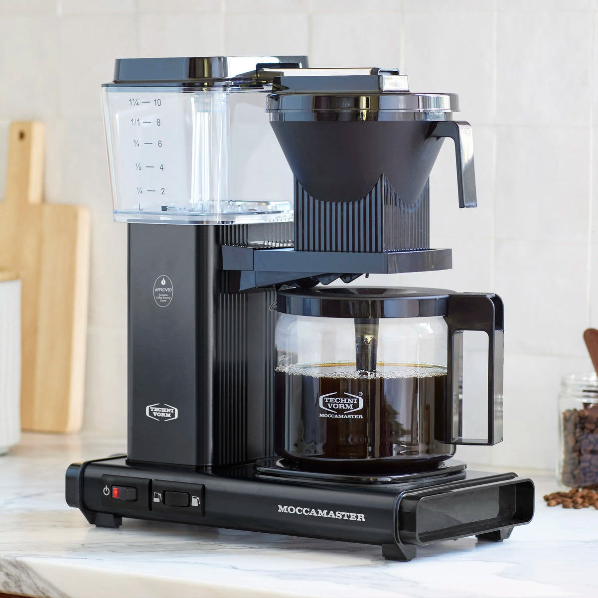 Black Moccamaster drip-stop coffee maker with glass carafe and measurement markings