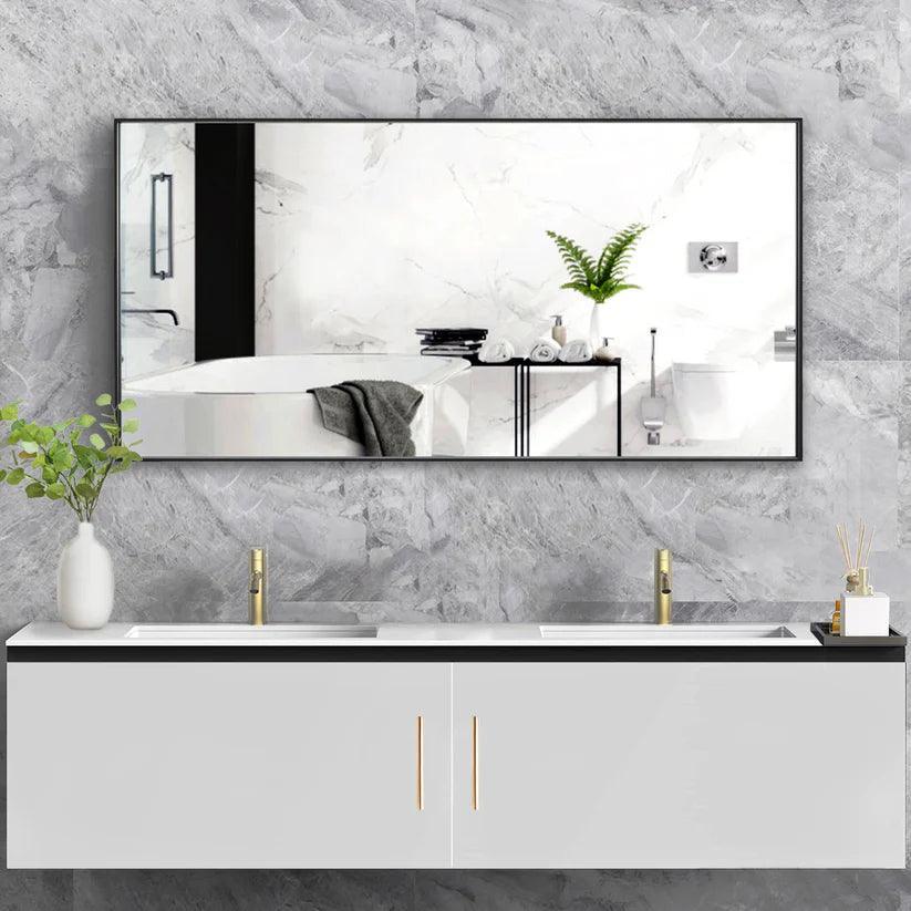 Rectangular wall mirror with black frame reflecting white bathroom sink area