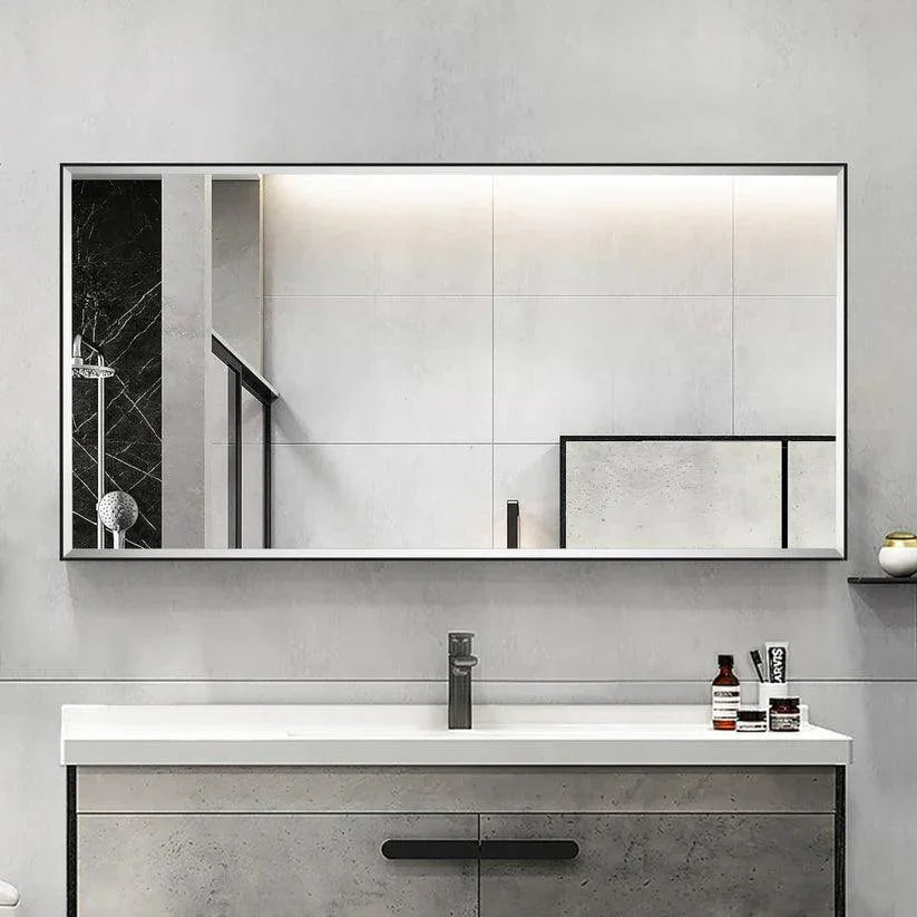Black framed wall mirror with beveled glass edge above a bathroom vanity.