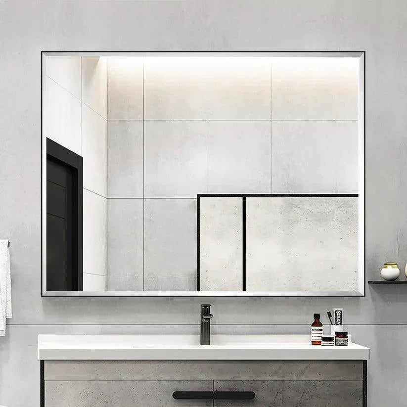 Black framed wall mirror with beveled glass edge mounted over a bathroom vanity.