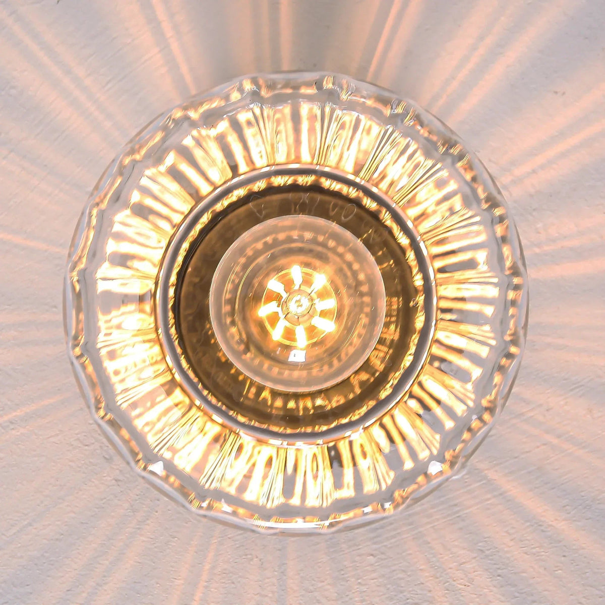 Ceiling light from below: golden ring and clear glass shade with glowing bulb