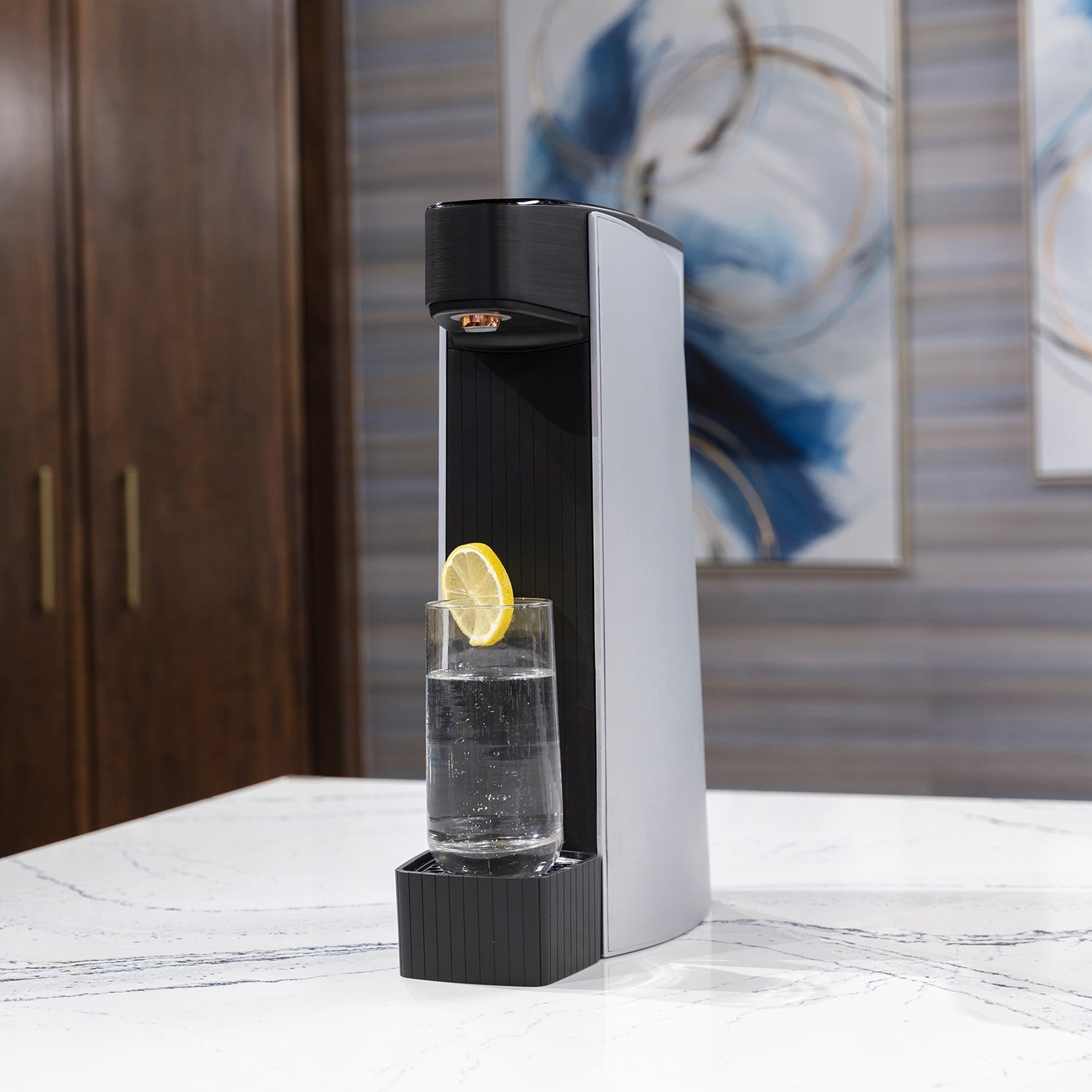 Carbon8 sparkling water maker with lemon slice on glass, pouring water, countertop scene
