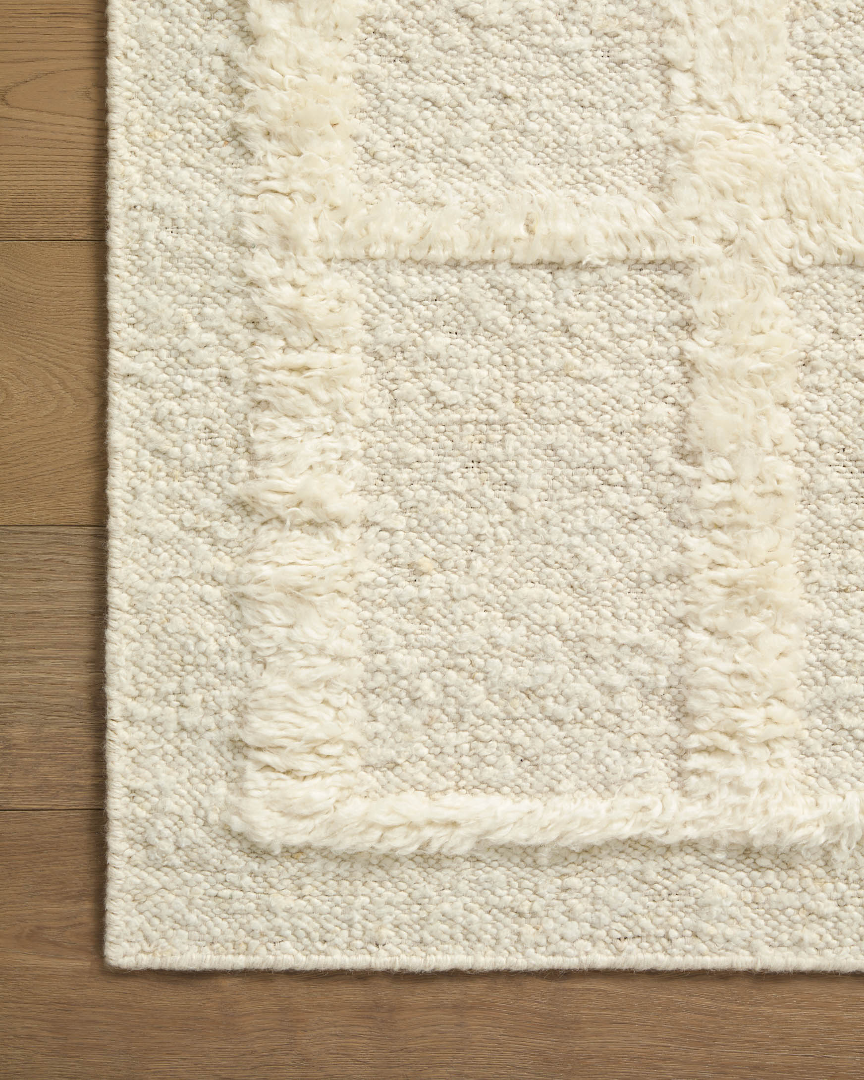 Ivory area rug with textured diamond-grid pattern and raised border
