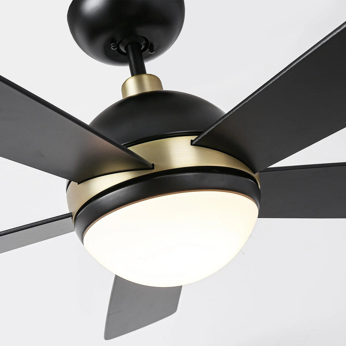 Ceiling fan with LED light, close-up of black blades and gold-rim light
