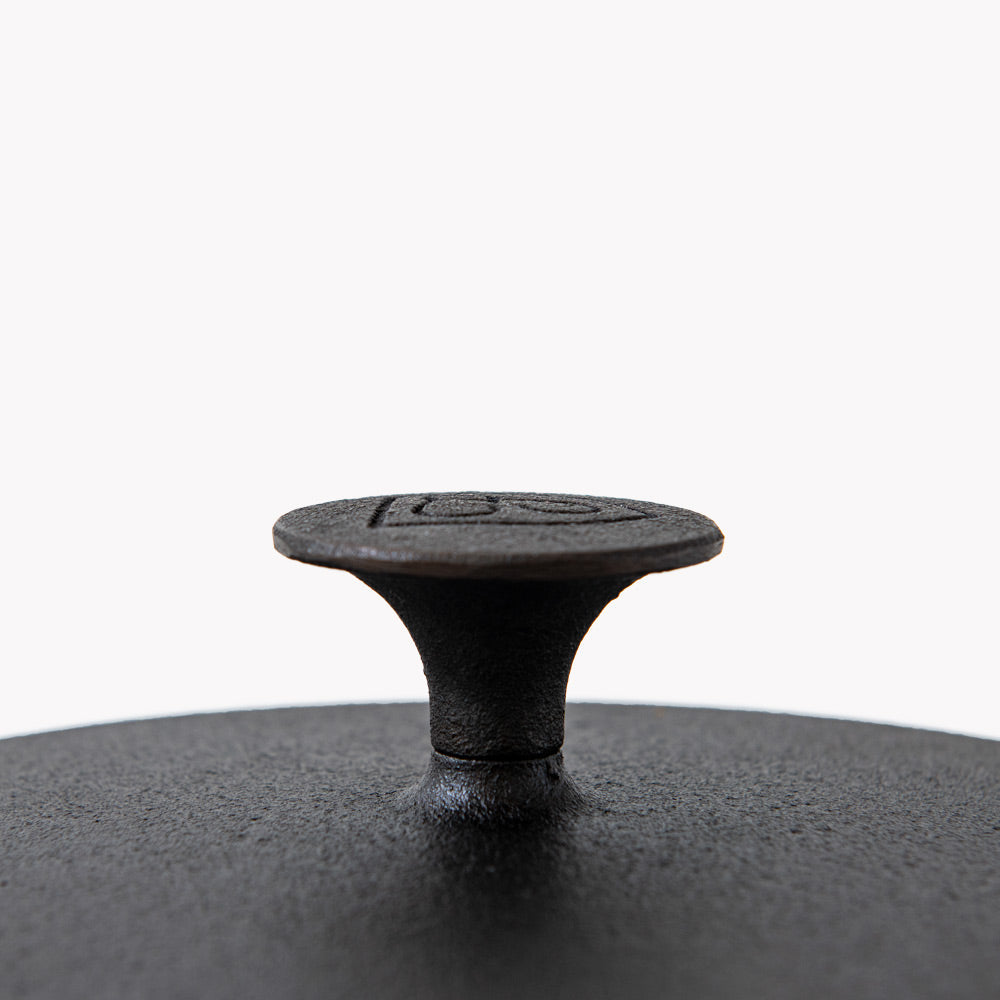 Cast-iron lid knob with embossed emblem on dark matte lid