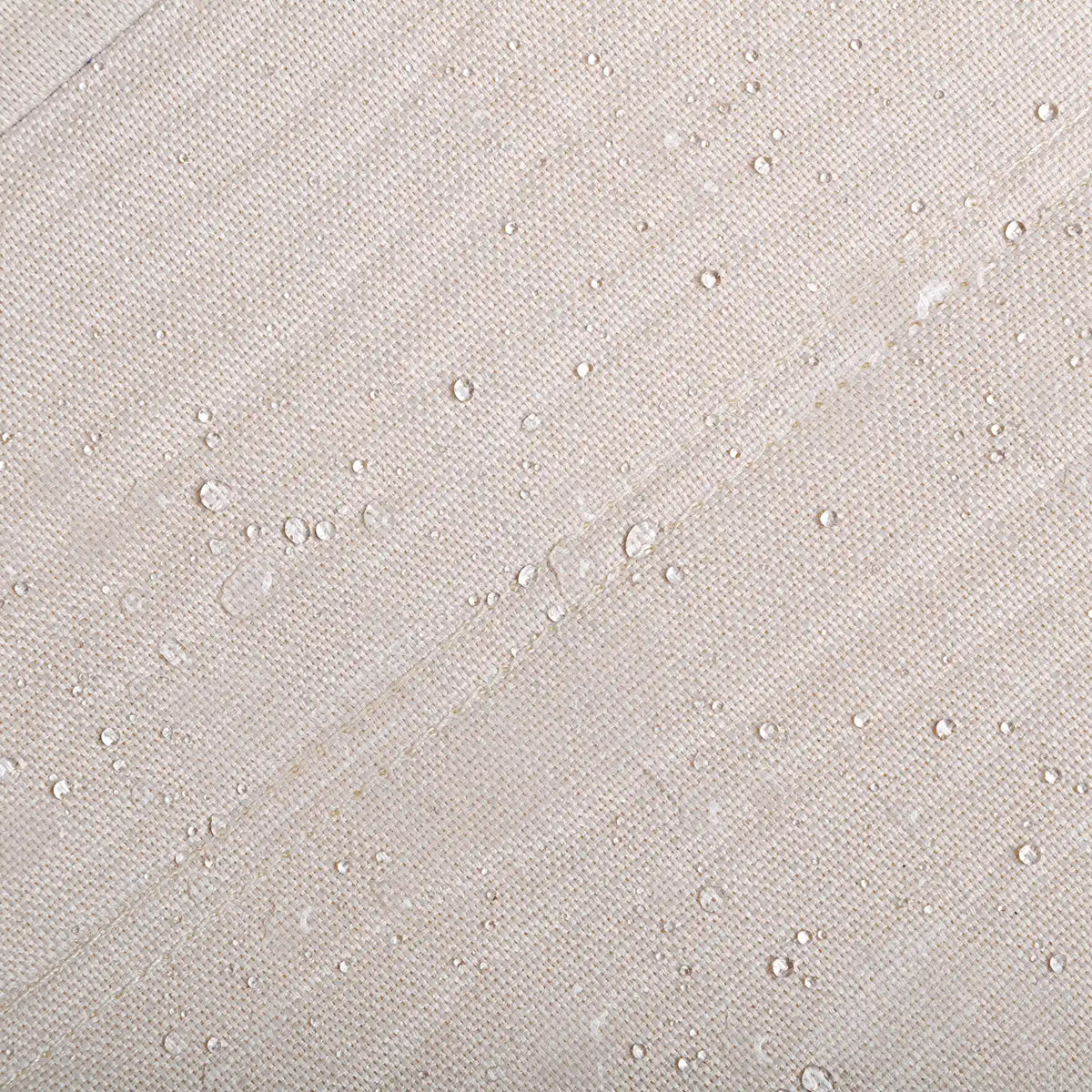 Beige textured fabric surface with small water-resistant bead-like marks