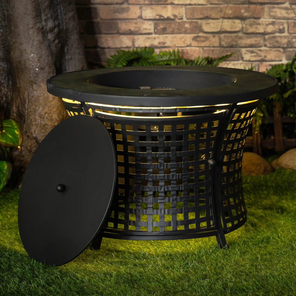 Black outdoor propane fire pit table with open round lid resting at the side