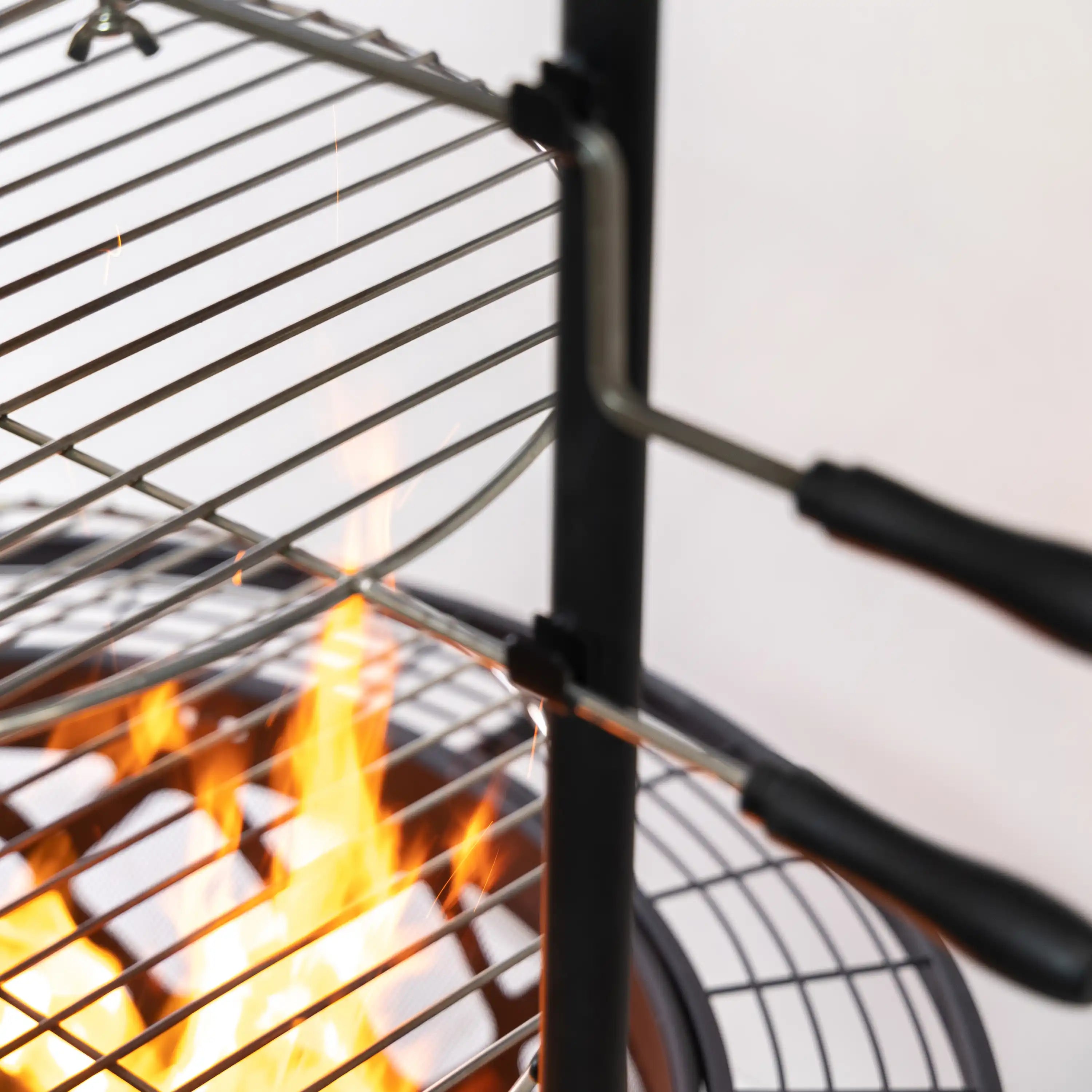 Close-up of rotisserie handle bar near the grill grates with flames below