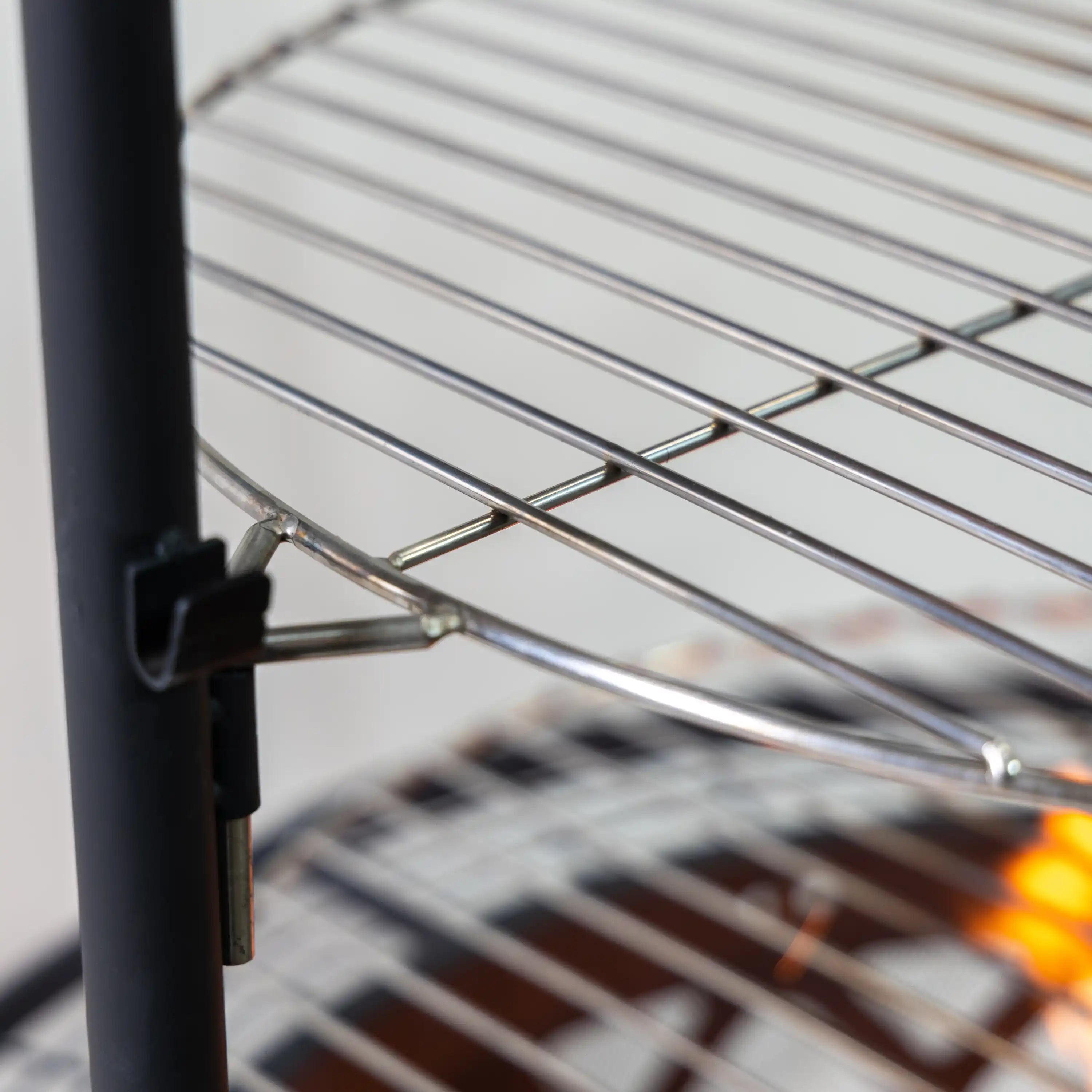 Close-up of top steel wire cooking grate and support bracket above the fire pit