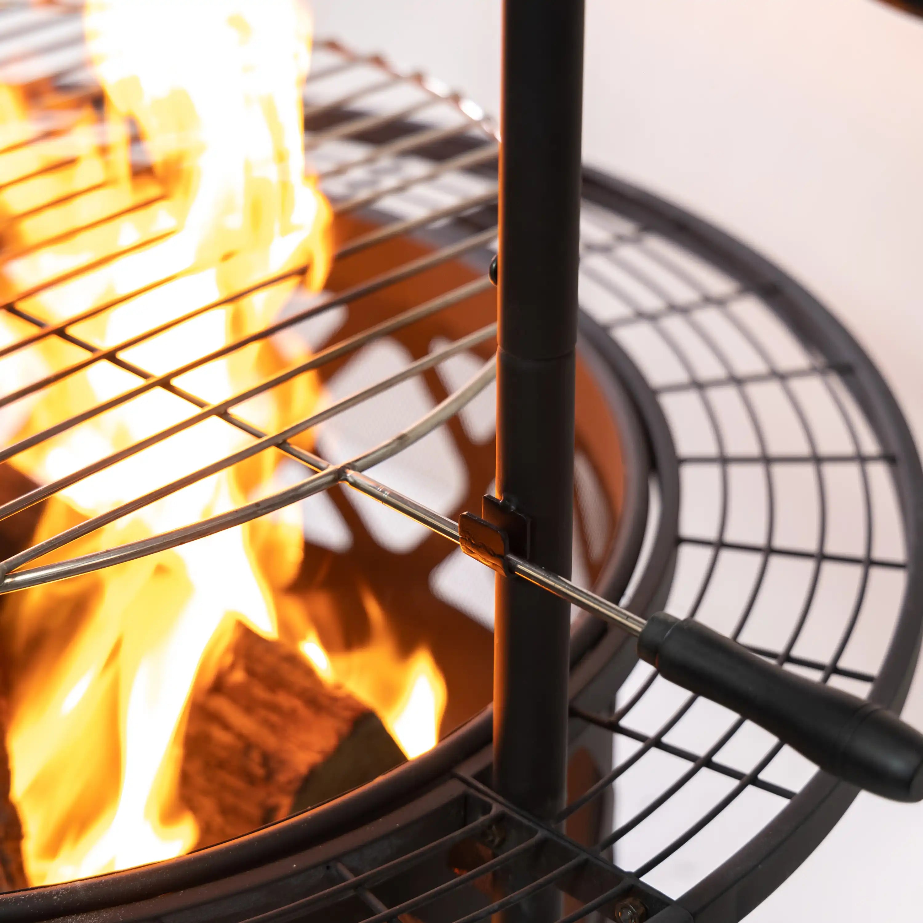 Rotisserie fire pit grill close-up with glowing flames behind the wire cooking grid