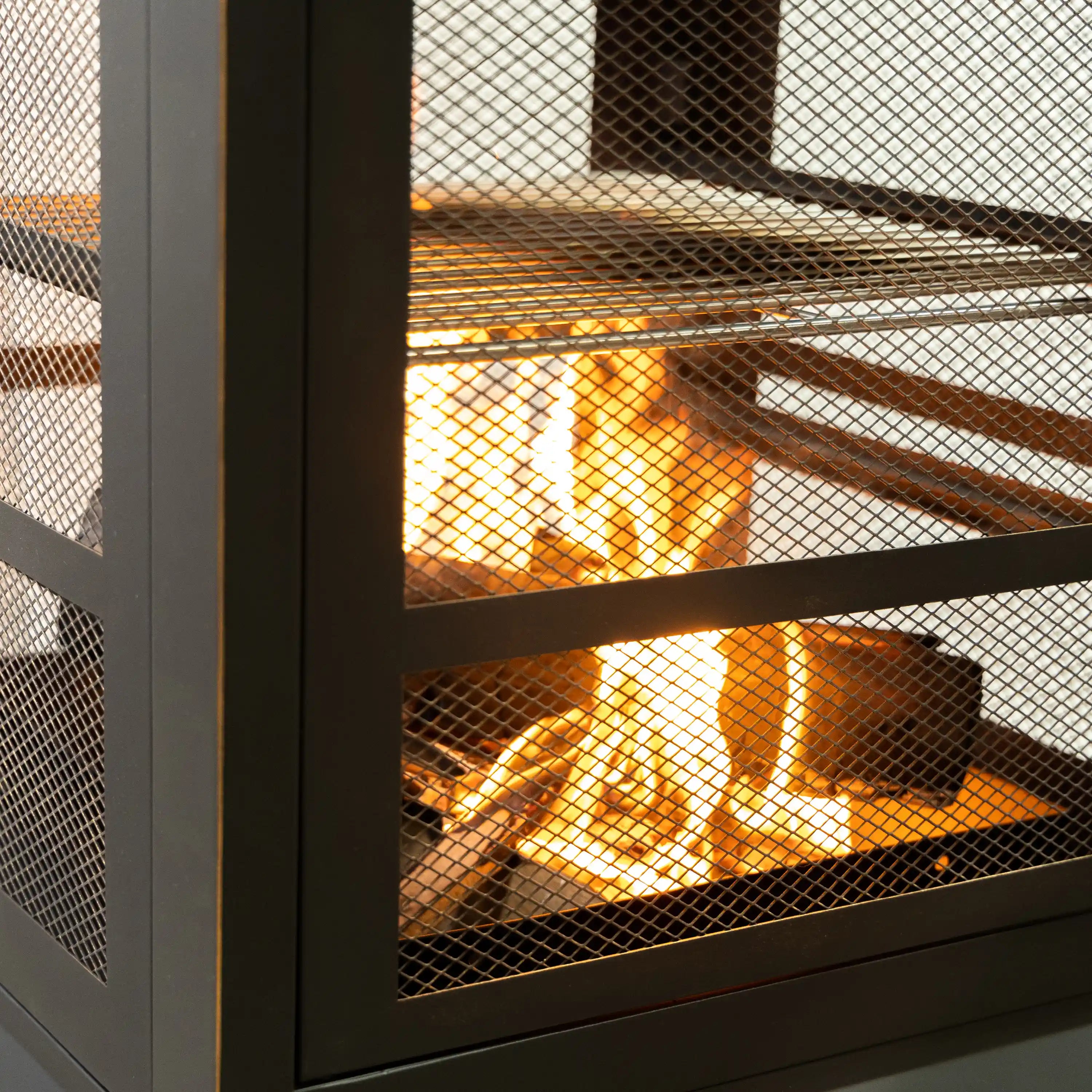Flames visible through mesh panels in the firebox of an outdoor steel woodburning fireplace