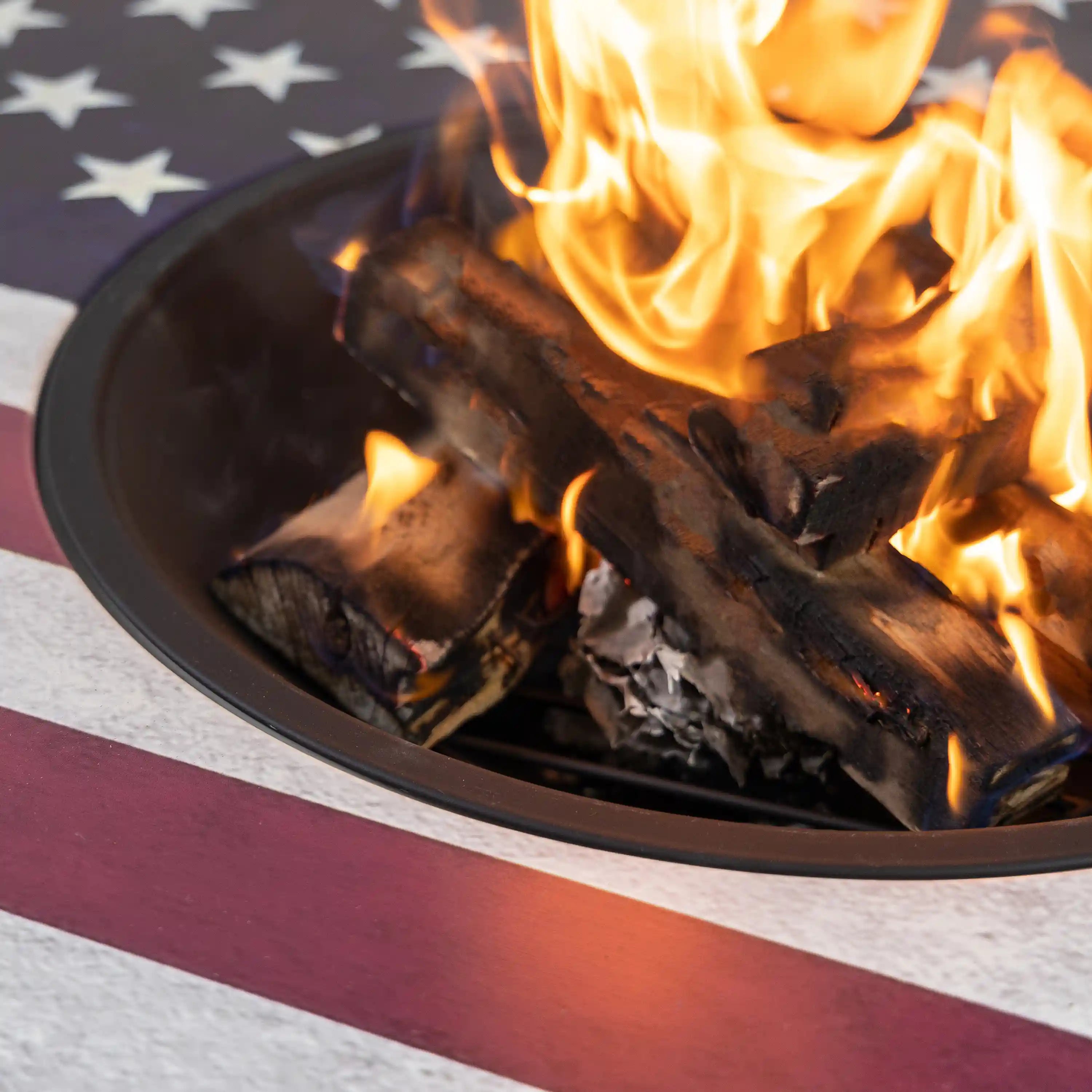 Close-up of flames burning inside a round black fire pit bowl with logs