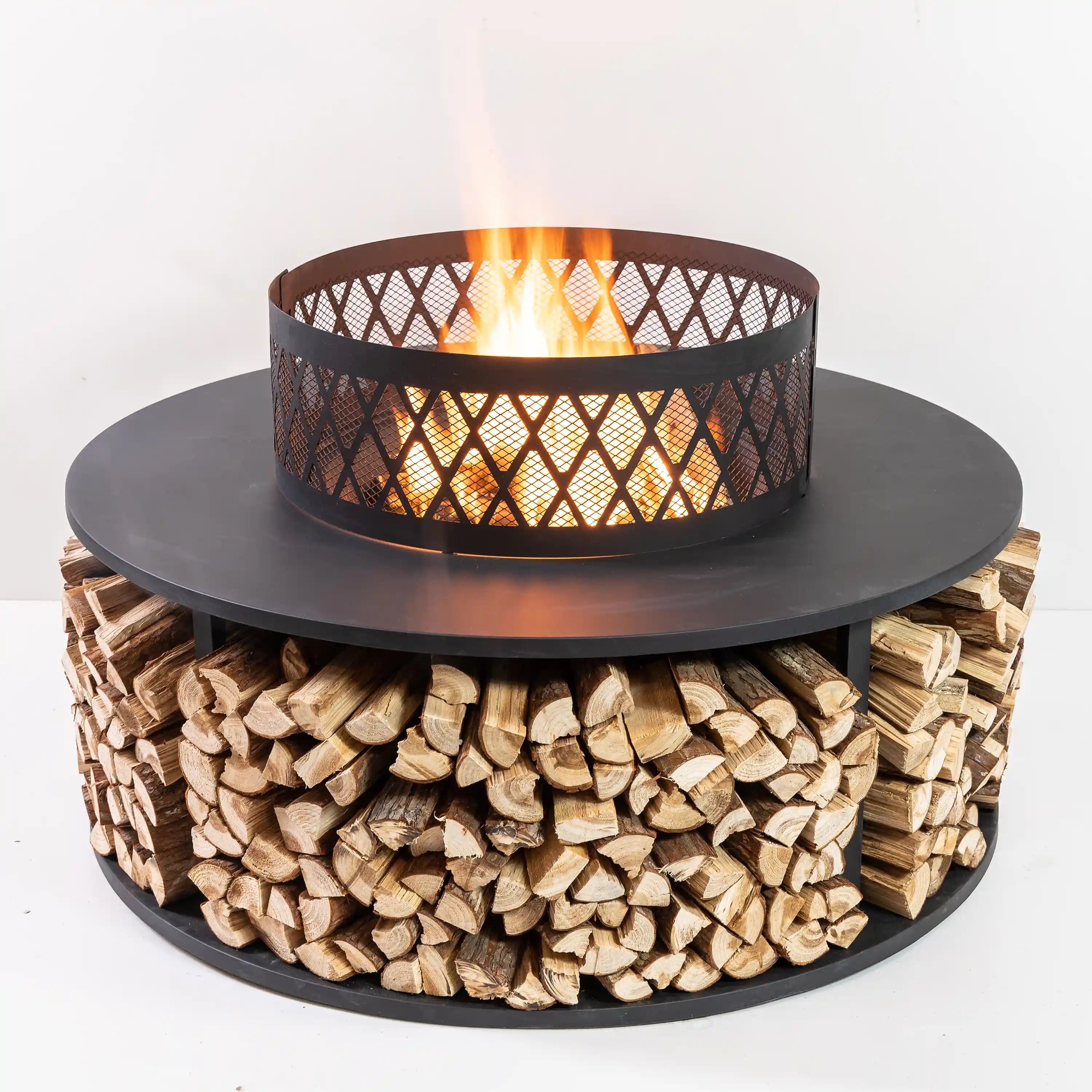Outdoor fire pit with log storage base, black round tabletop and mesh fire bowl.