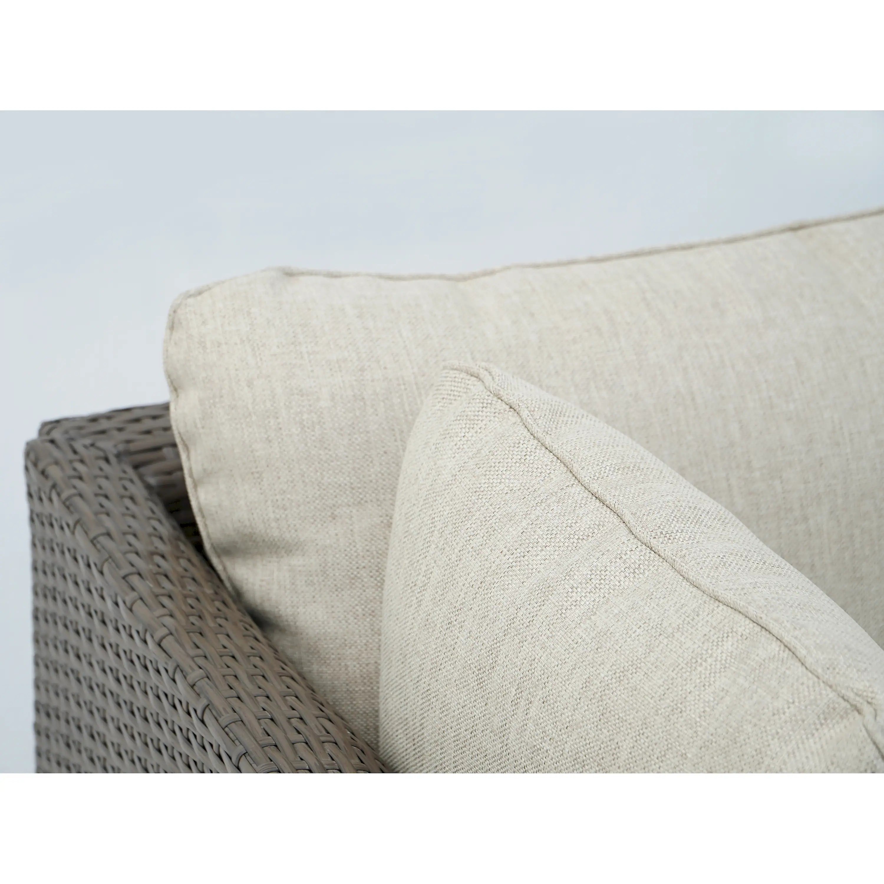 Outdoor wicker sofa cushion detail with light beige fabric and stitched seams