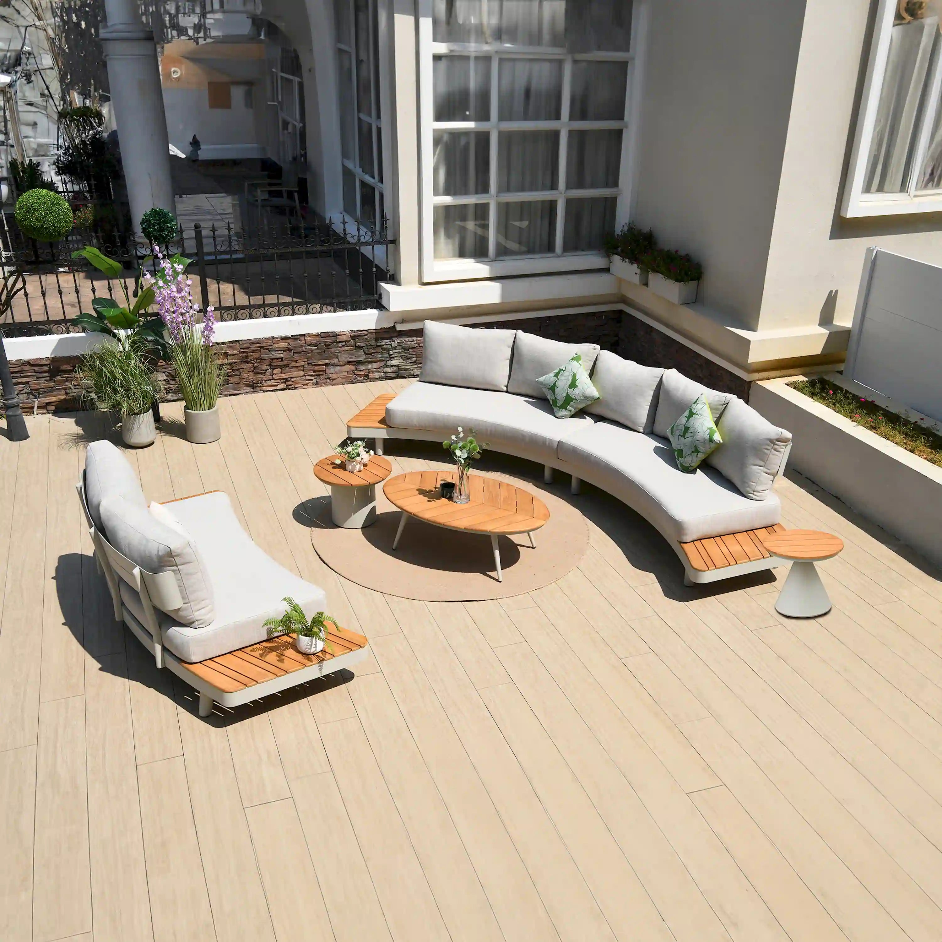 Outdoor sectional seating set with cream cushions, teak slat accents, and round table.