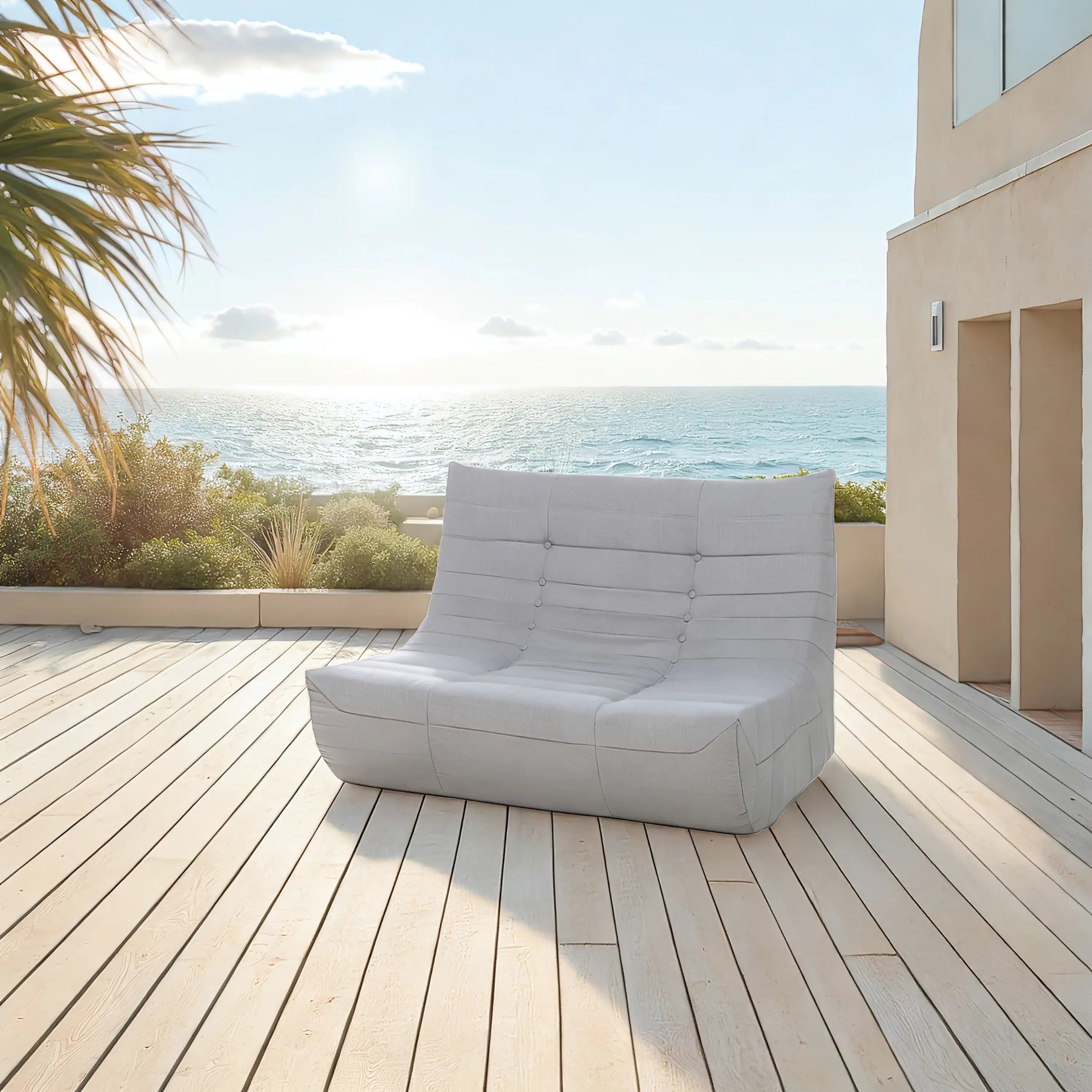 Gray outdoor sofa with tufted button back on wooden deck