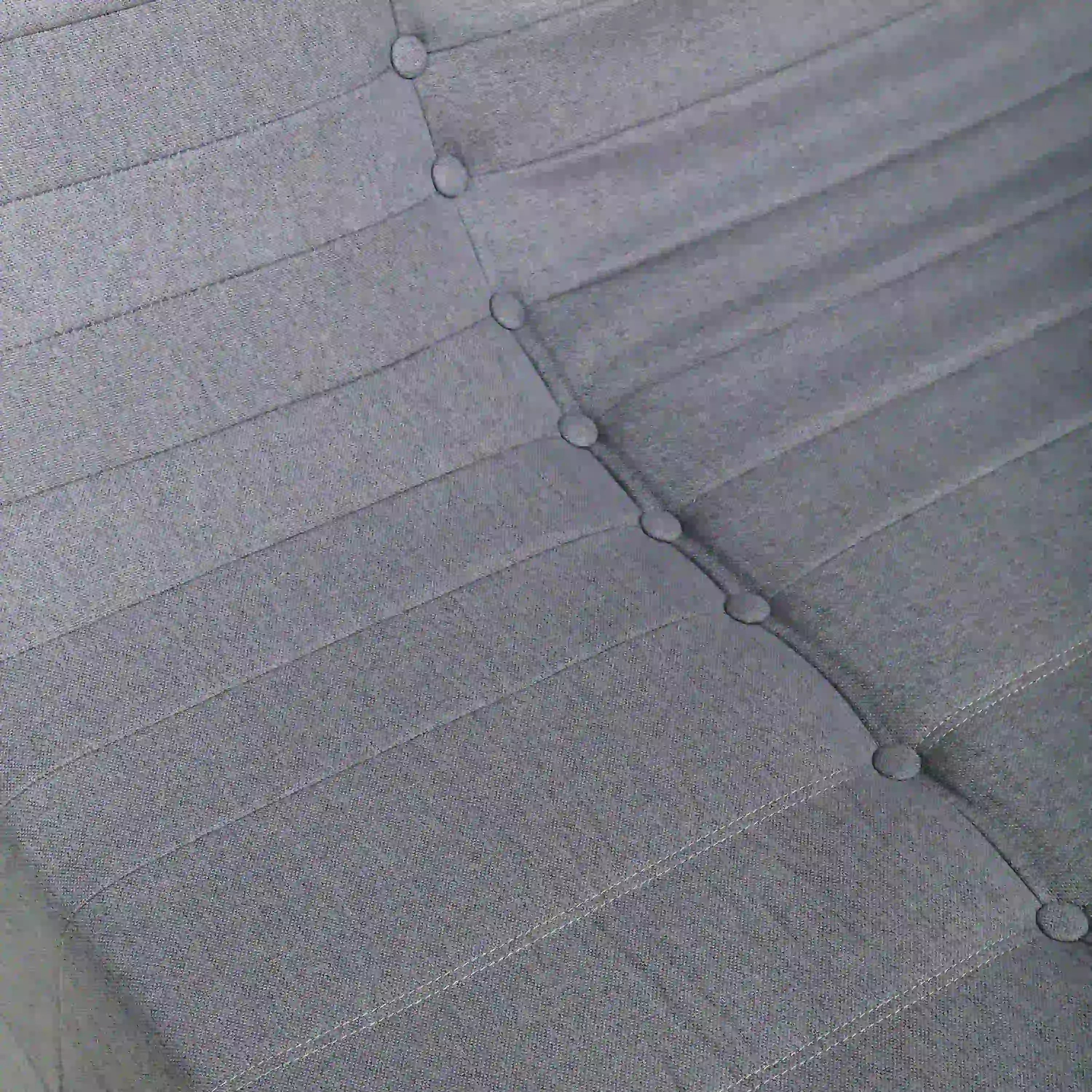 Gray tufted sofa back with round button details and horizontal stitch lines