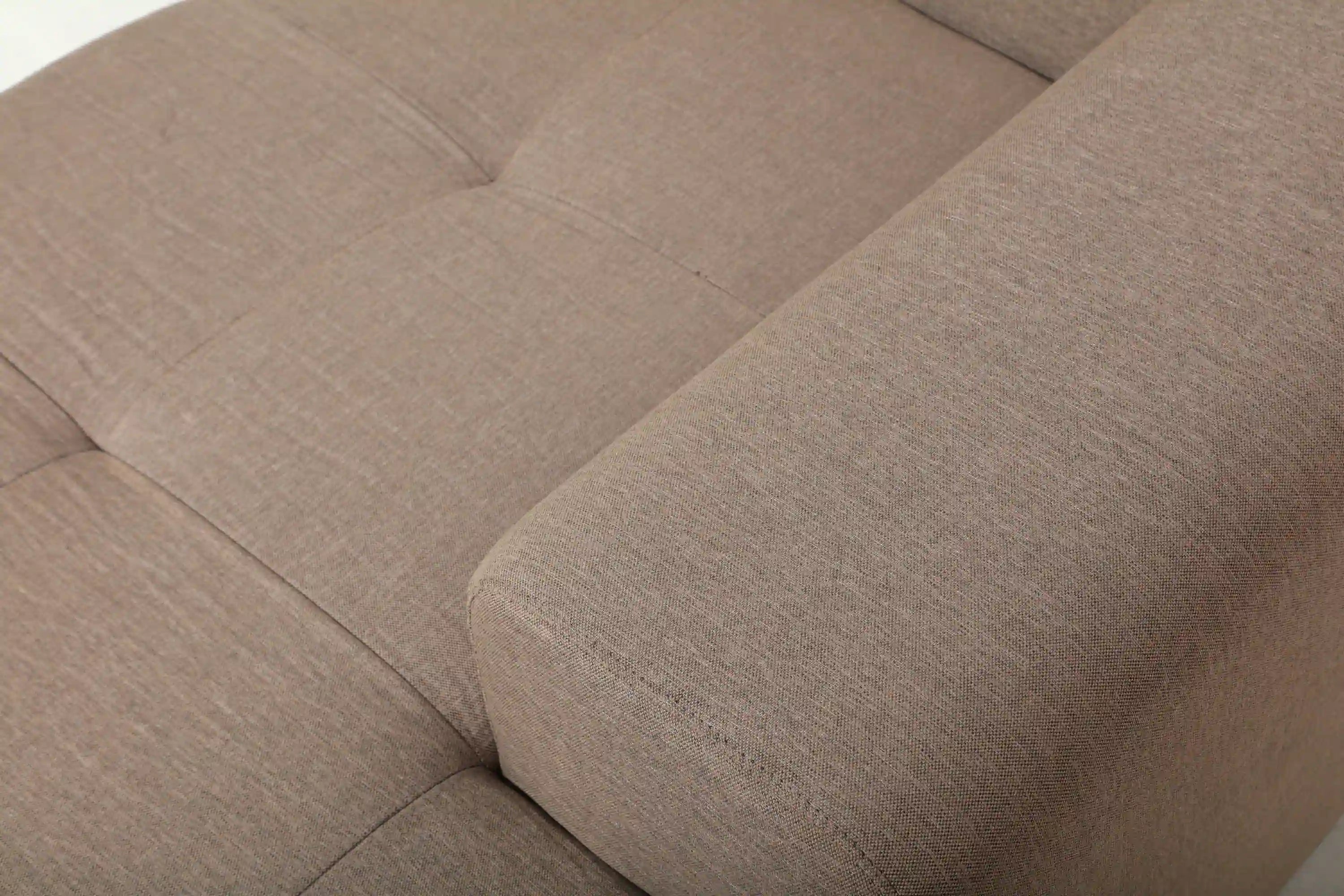 Tan sectional sofa seat cushion with stitched lines and curved armrest