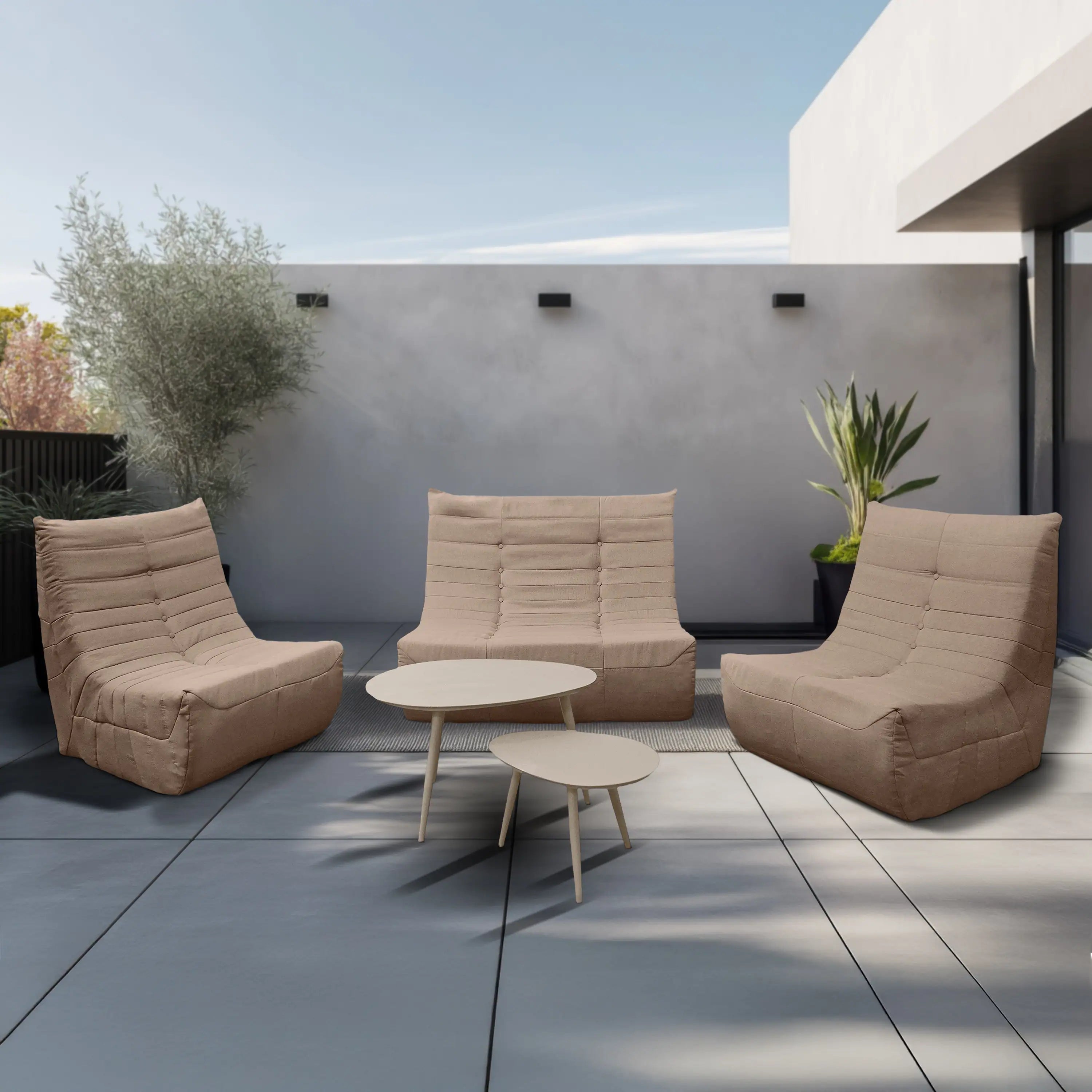 Tan outdoor loveseat set with two chairs and two round side tables on a patio.