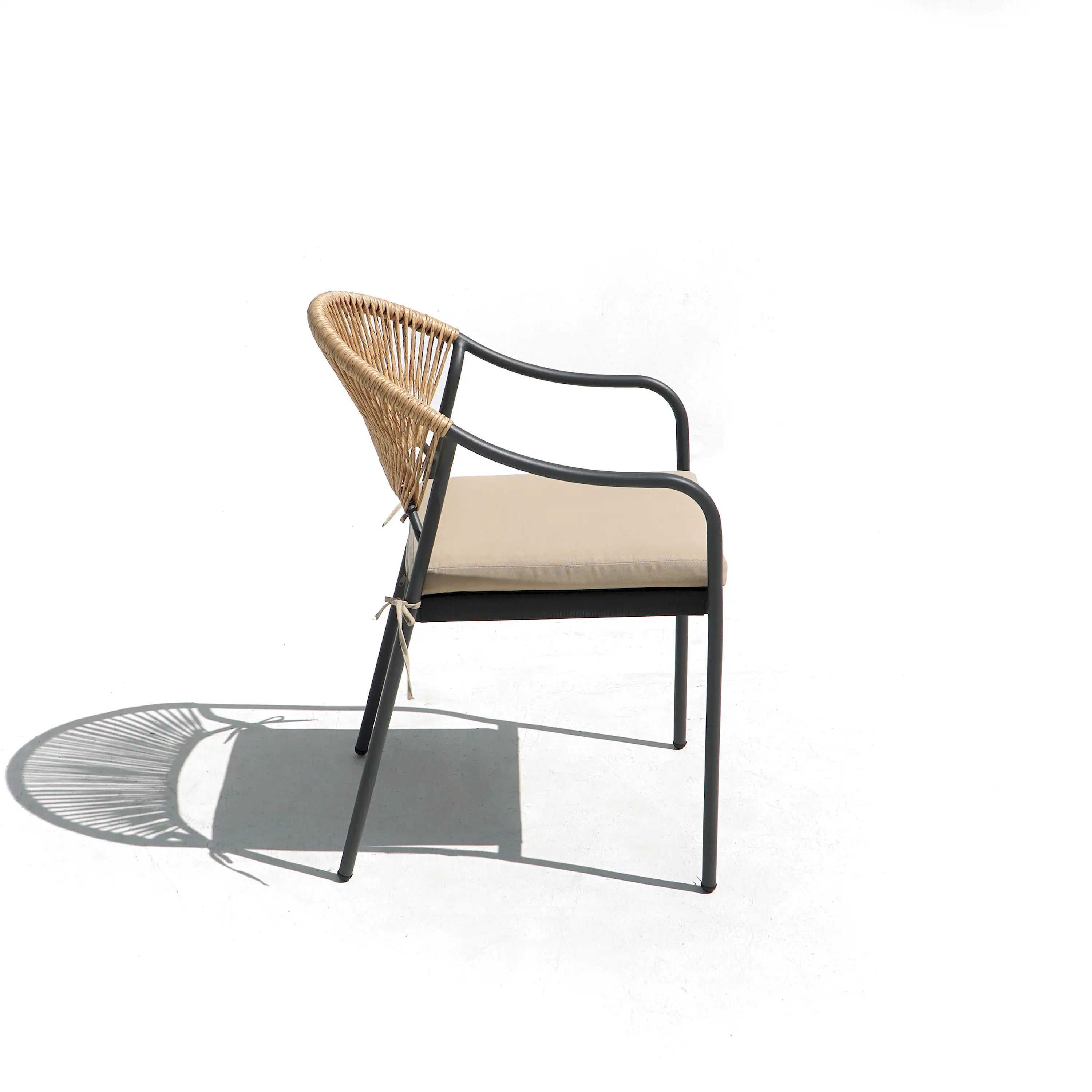 Outdoor dining chair with woven wicker seat back, beige cushion, and dark metal arms.