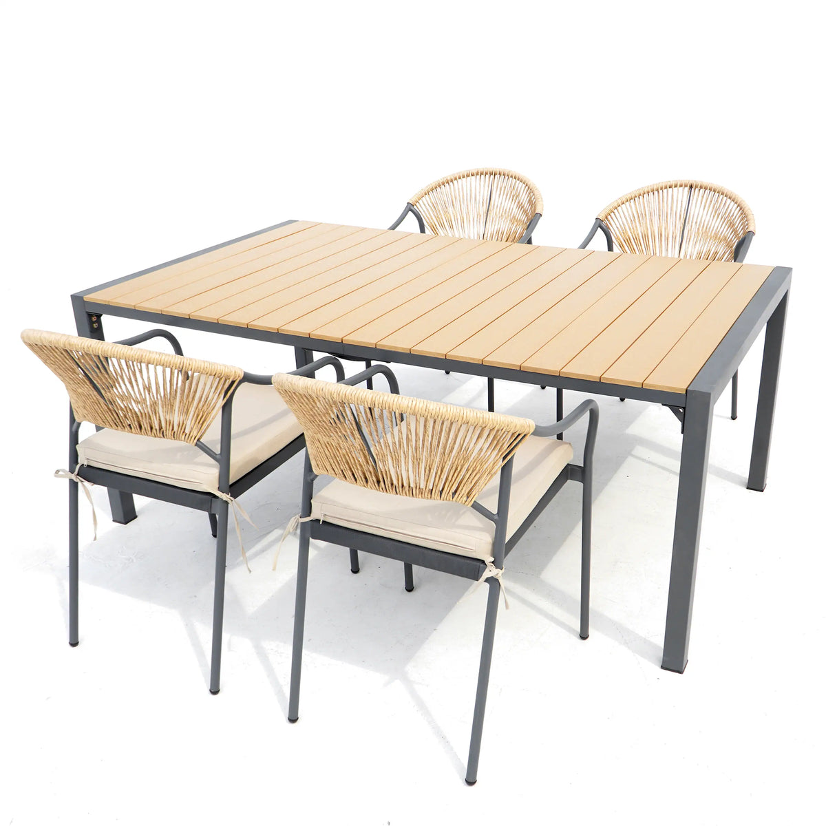 Rectangular outdoor dining table with wood slats and four wicker chairs with beige cushions.
