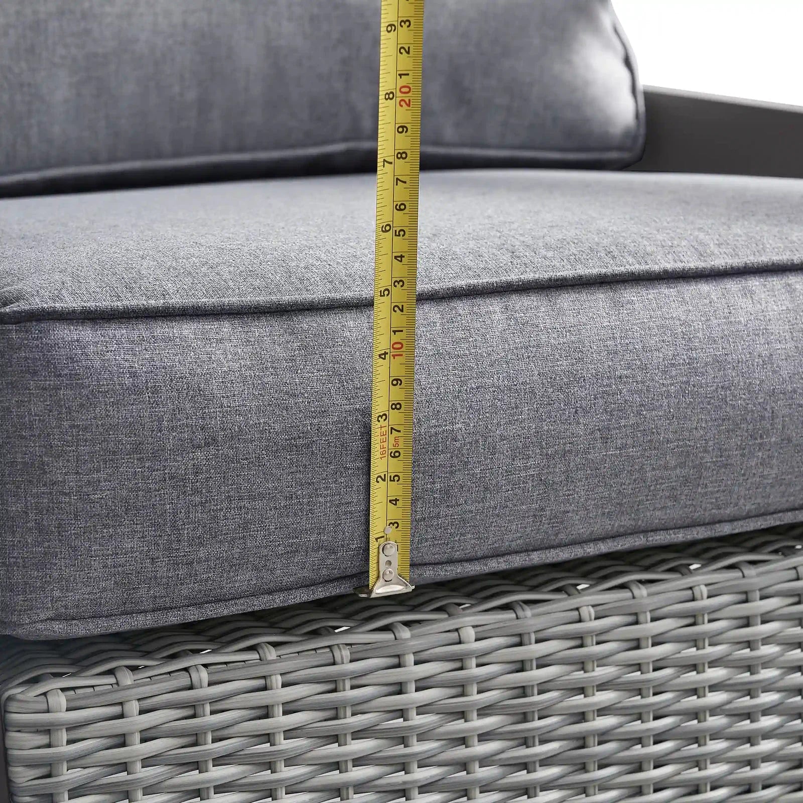Measuring tape on gray cushion above gray woven wicker base