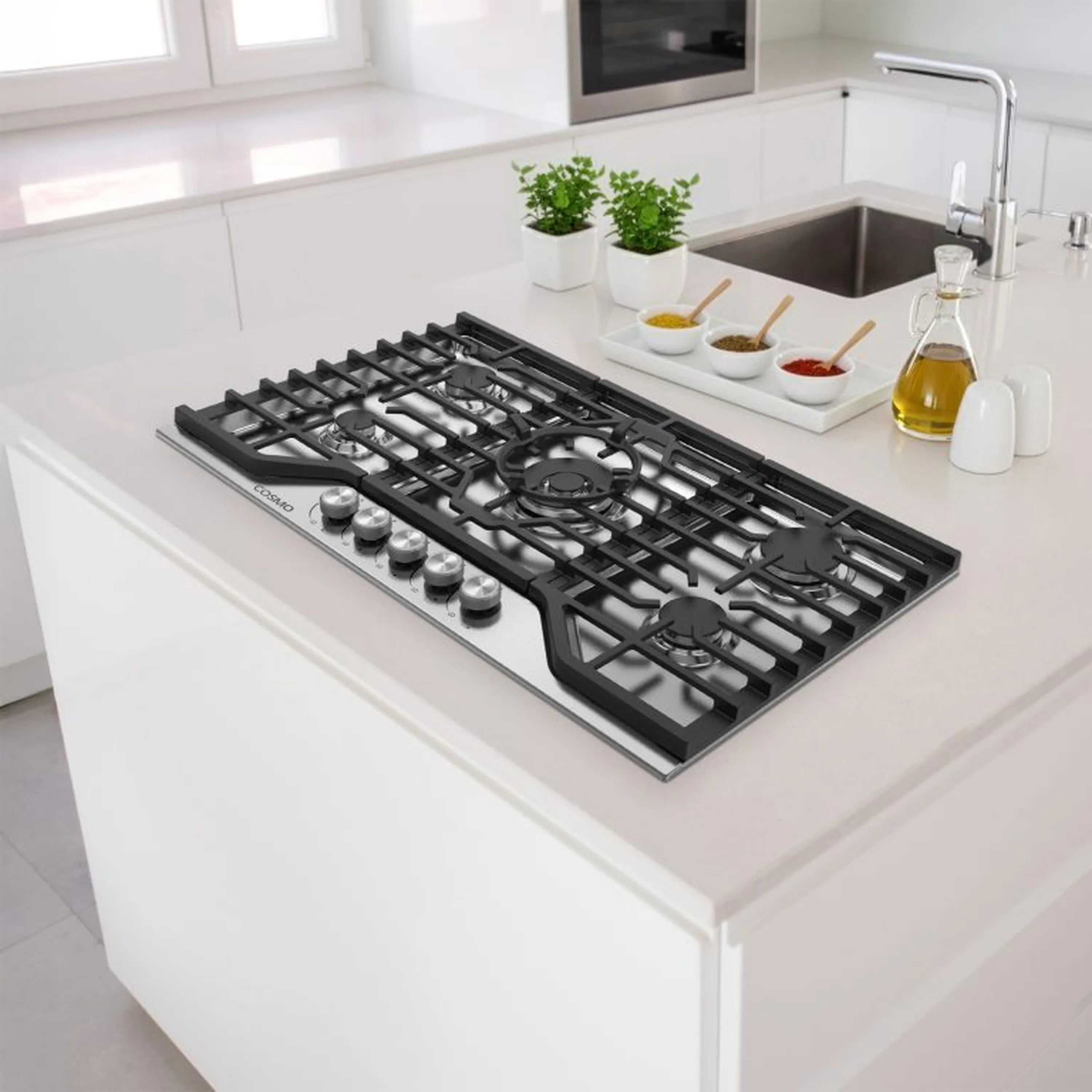 Stainless steel gas cooktop on countertop with black grates and four front knobs