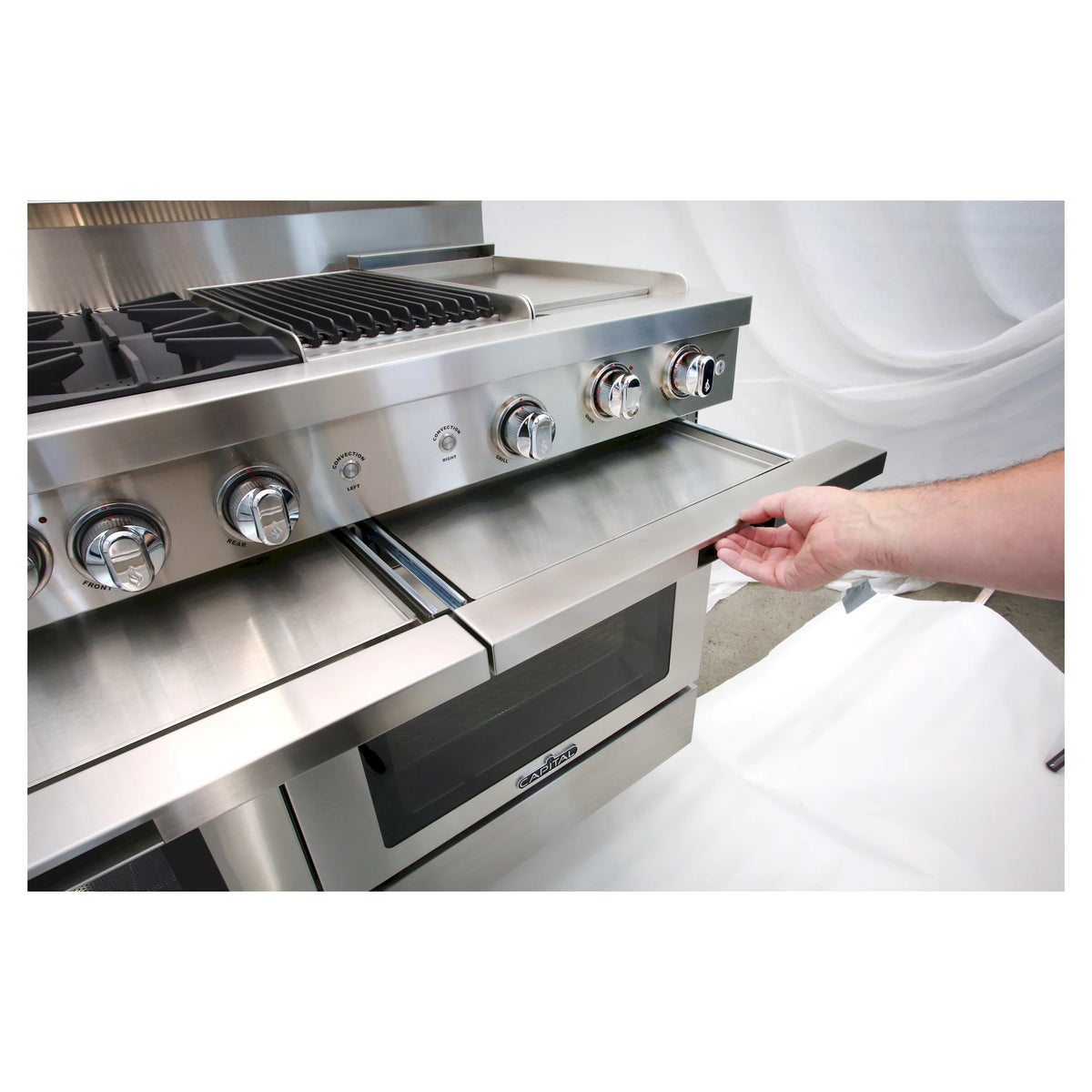 Stainless steel gas range with open lower drawer and burner knobs with grill