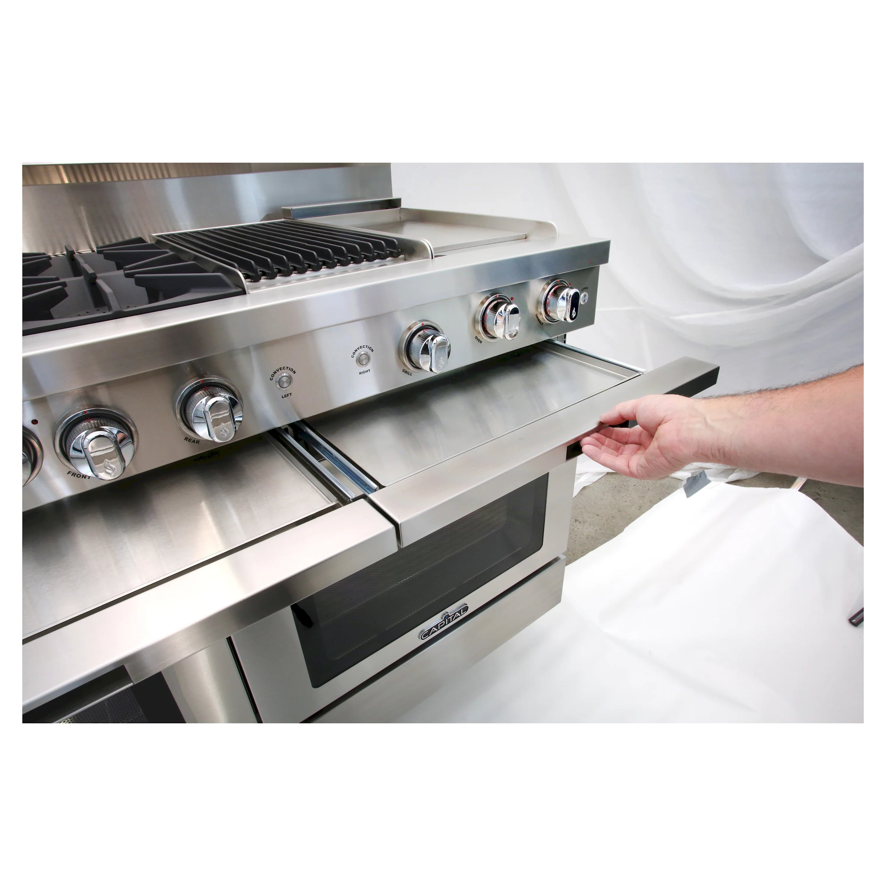 Stainless steel gas range with griddle drawer slid open, showing internal storage space