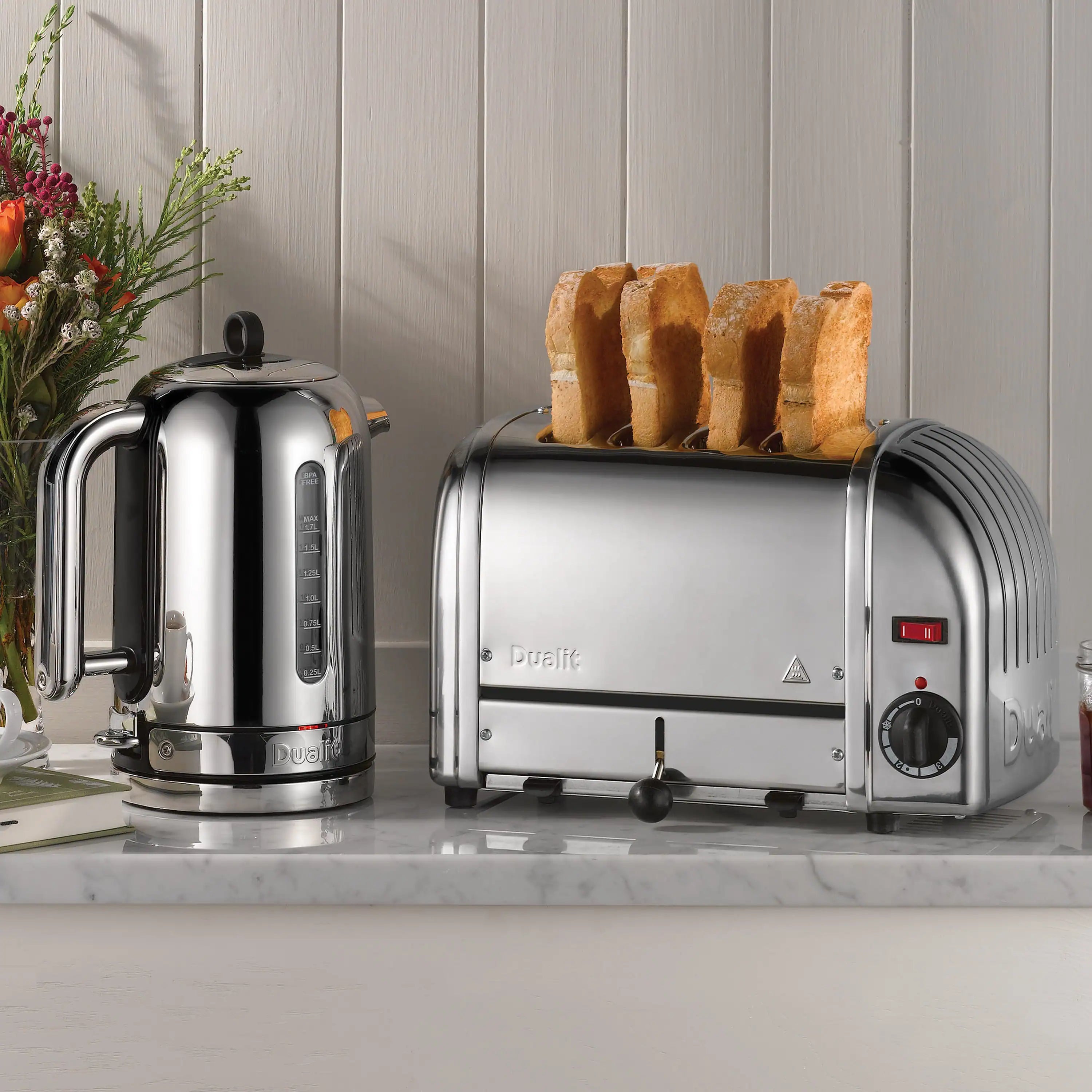 Dualit polished chrome electric kettle with black handle and control base on kitchen counter.