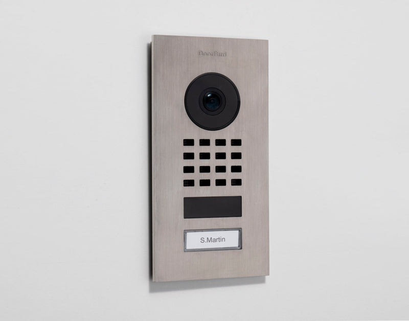 DoorBird D1101V brushed-metal video intercom with camera, keypad, and name label