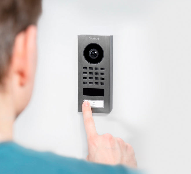 DoorBird D1101V video intercom with camera, keypad grid, and finger pressing button