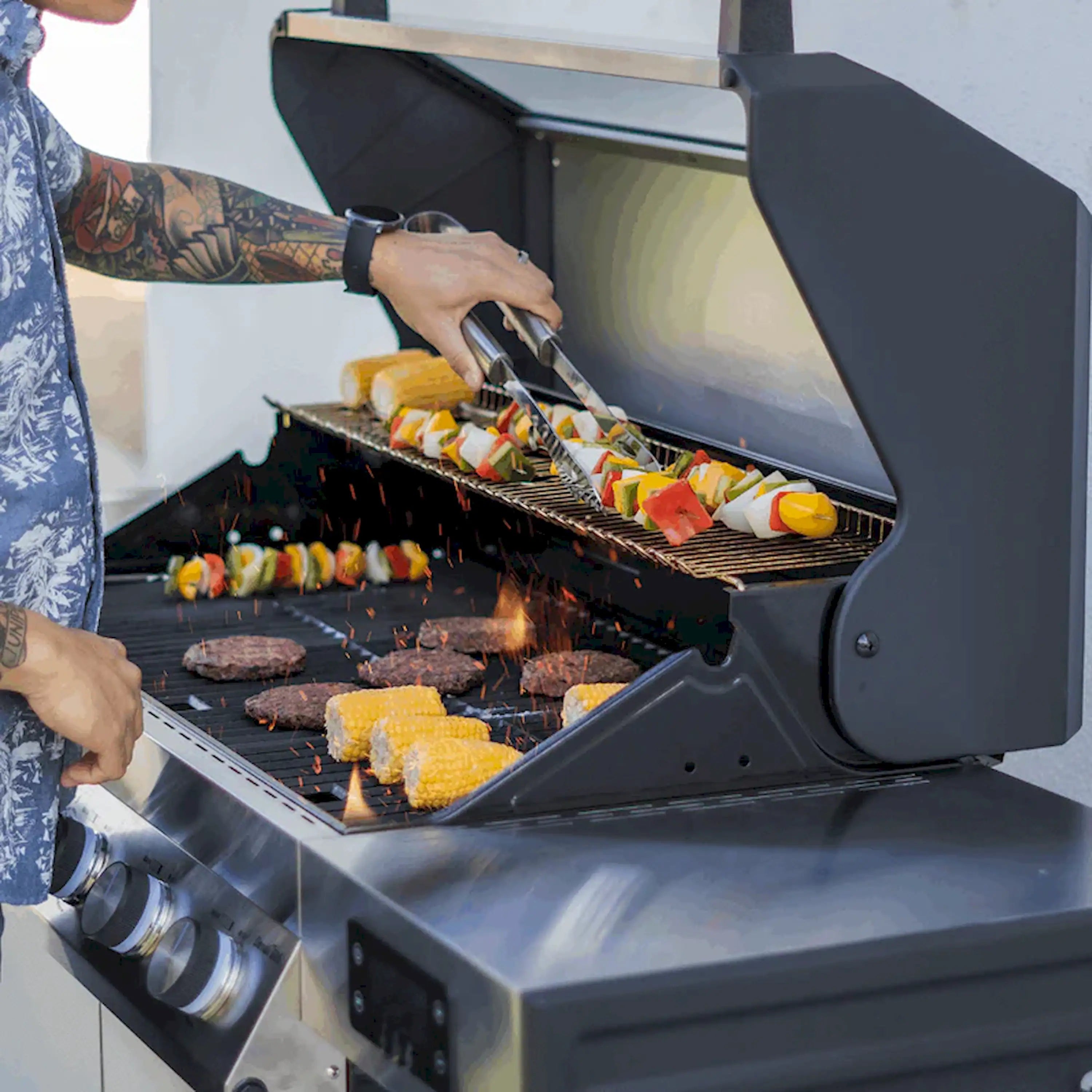 Stainless steel propane gas grill with food cooking on open black grates