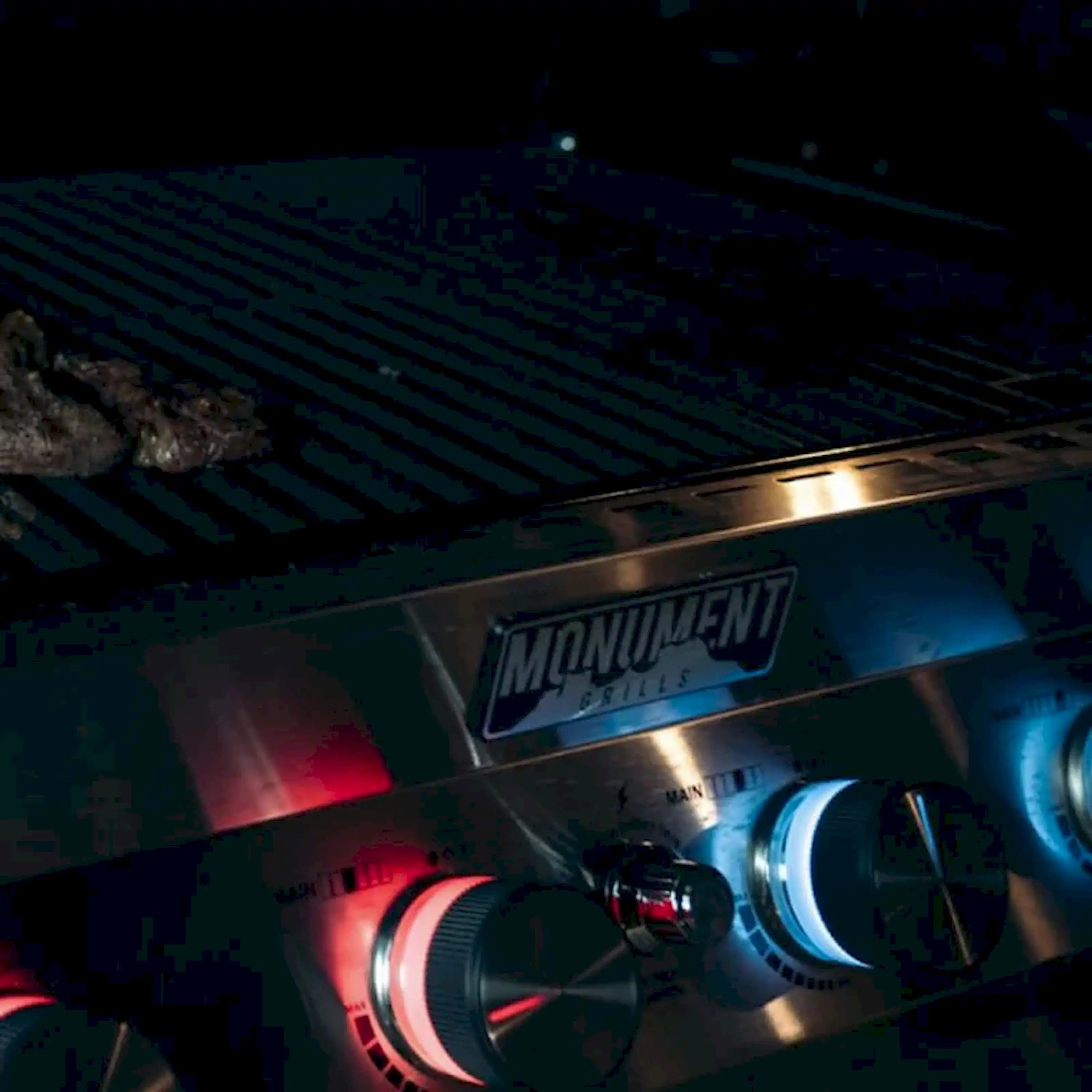 Stainless gas grill burner control area with MONUMENT GRILLS logo