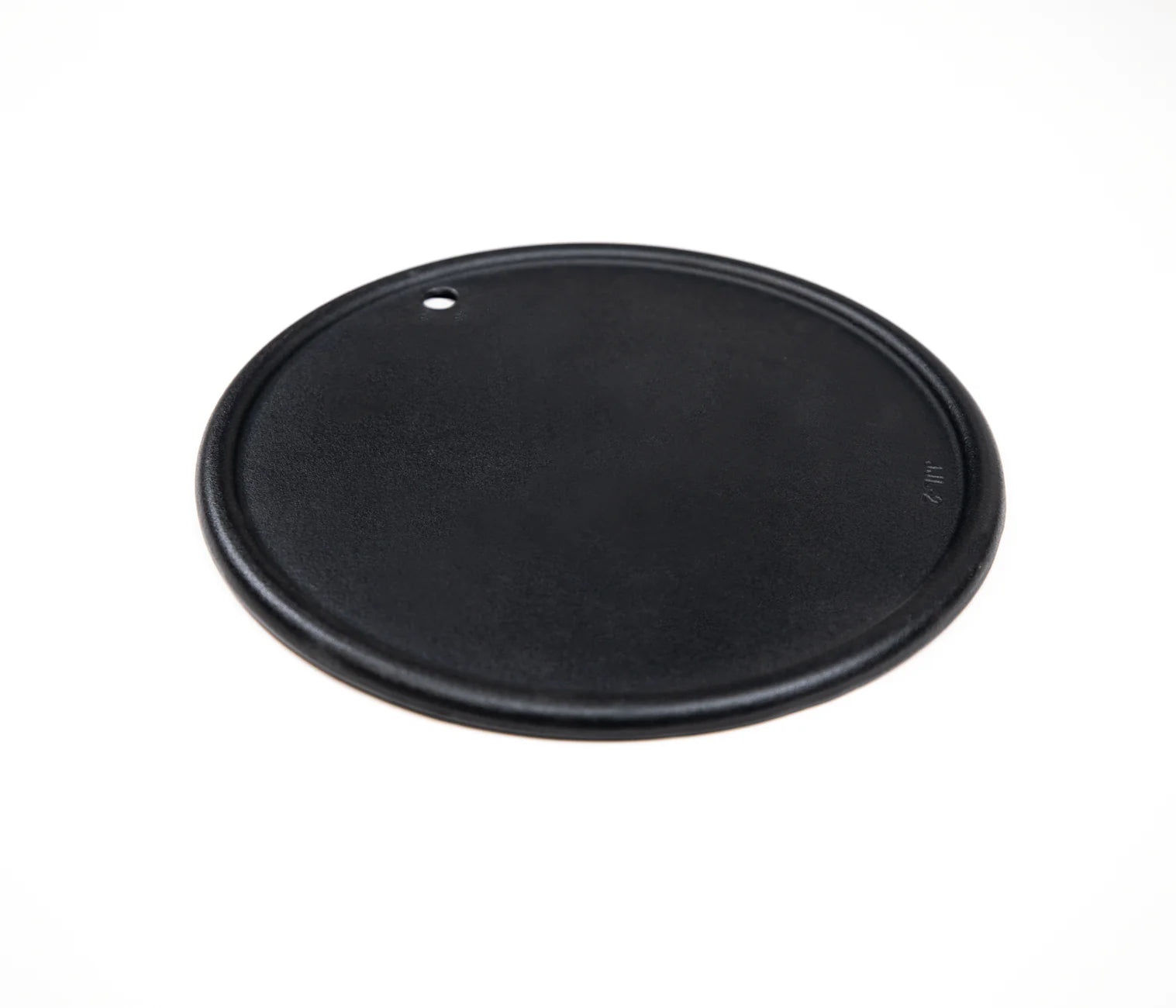 Round cast iron cooking plate, black underside with mounting hole and smooth surface