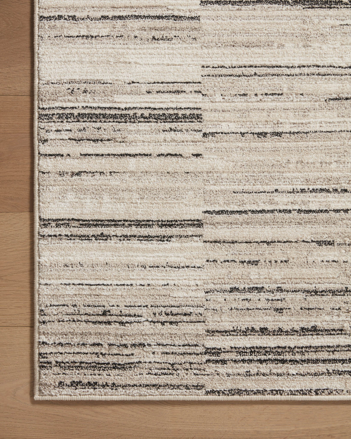 Charcoal and sand area rug corner with distressed horizontal stripes and border