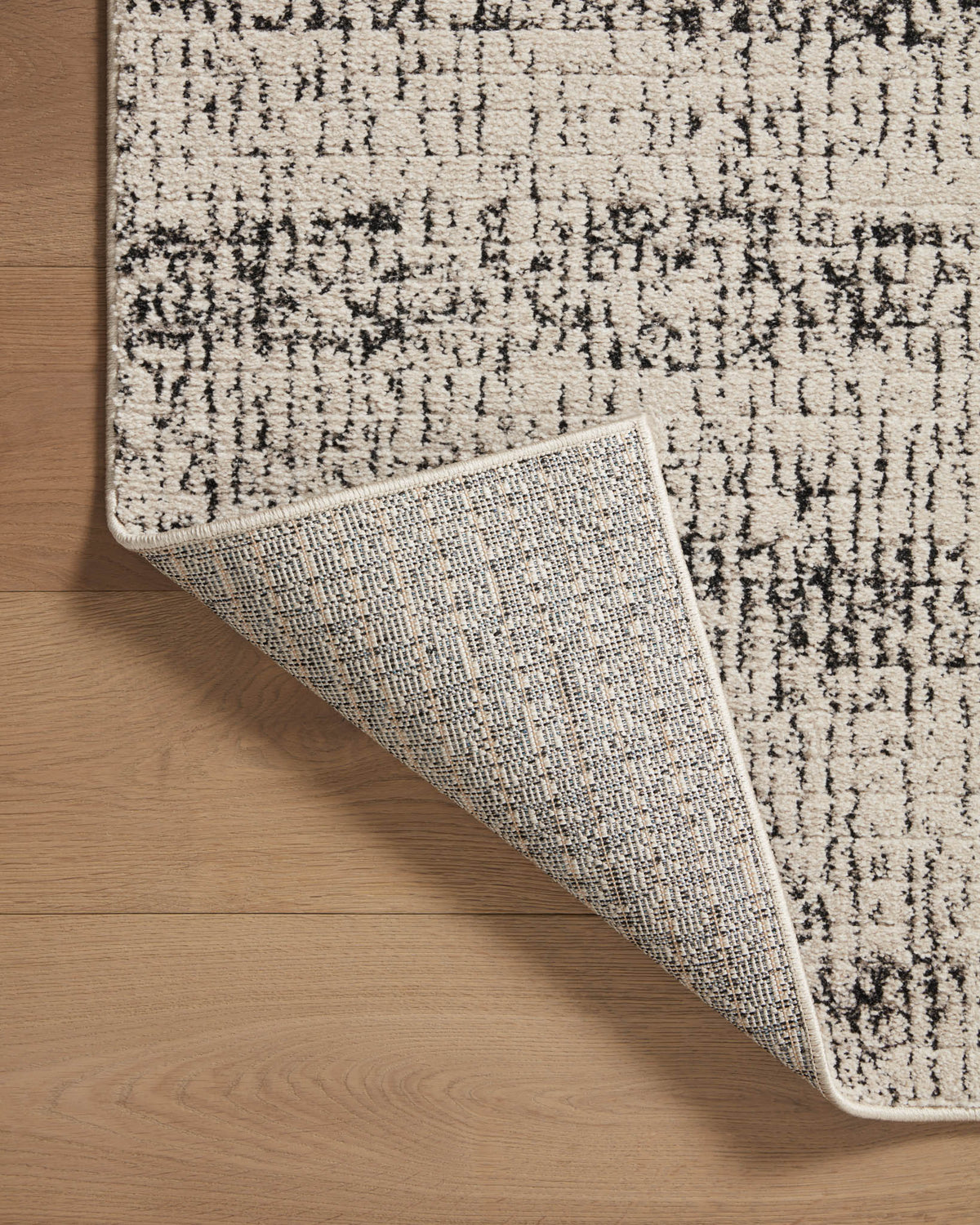 Oatmeal and charcoal rug corner detail with textured weave and stitched edge