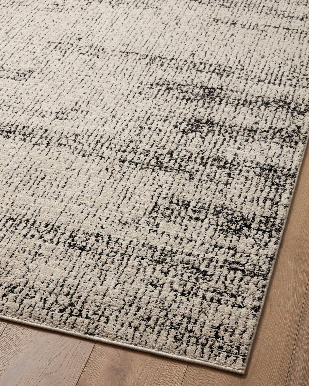 Oatmeal and charcoal area rug angled view showing dense distressed abstract lines