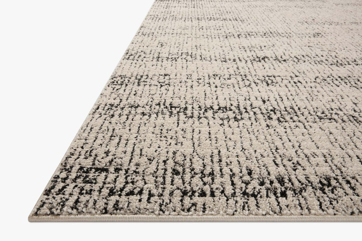 Oatmeal and charcoal area rug with distressed woven texture, corner view.
