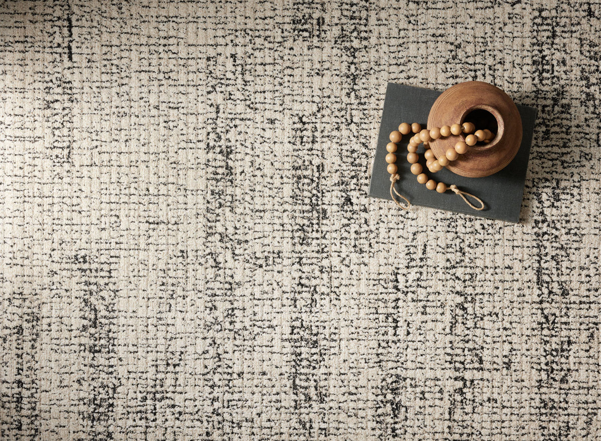 Oatmeal and charcoal low-pile rug texture with dense distressed motif in close-up