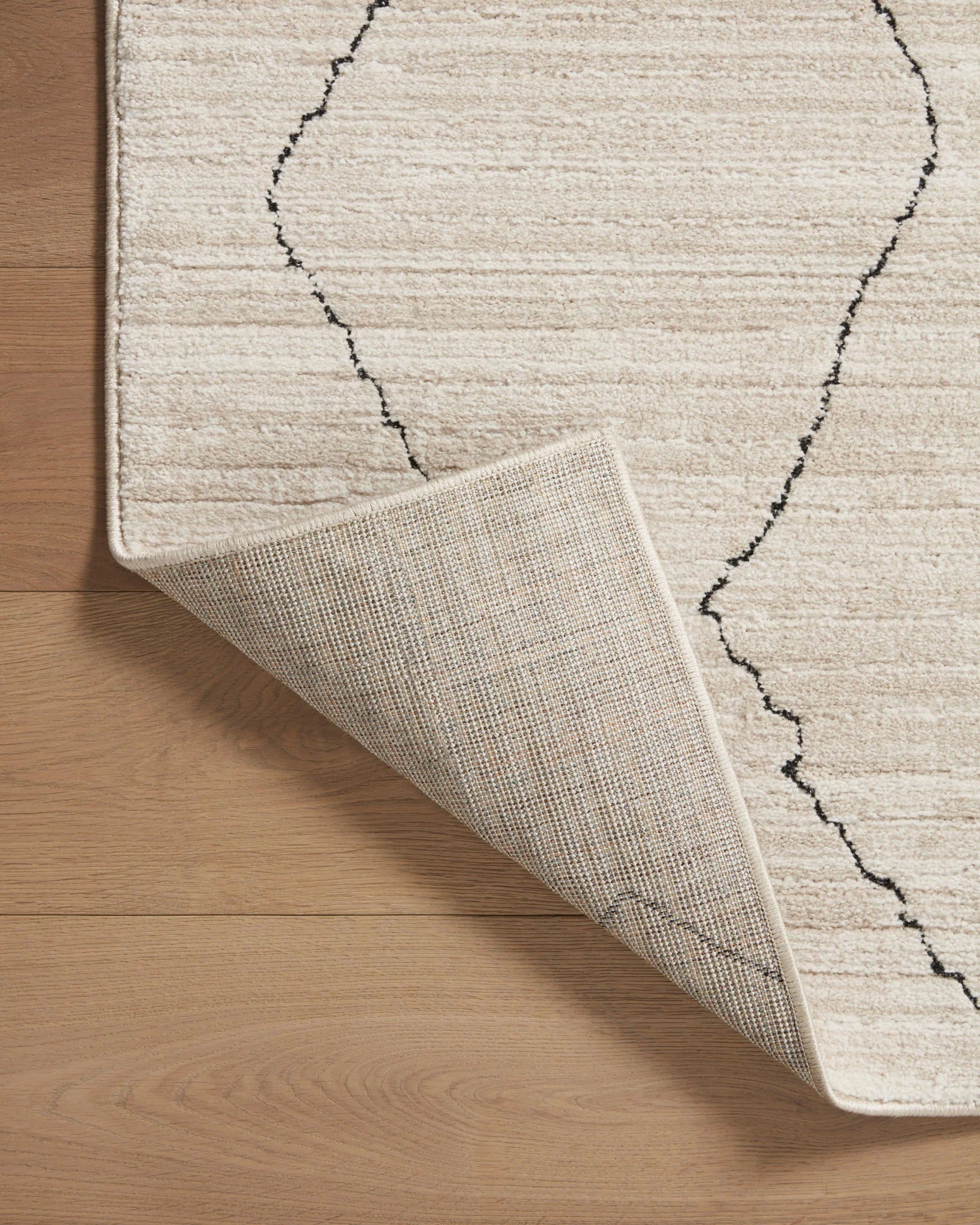 Sand runner rug showing underside and rolled hem with charcoal pattern lines