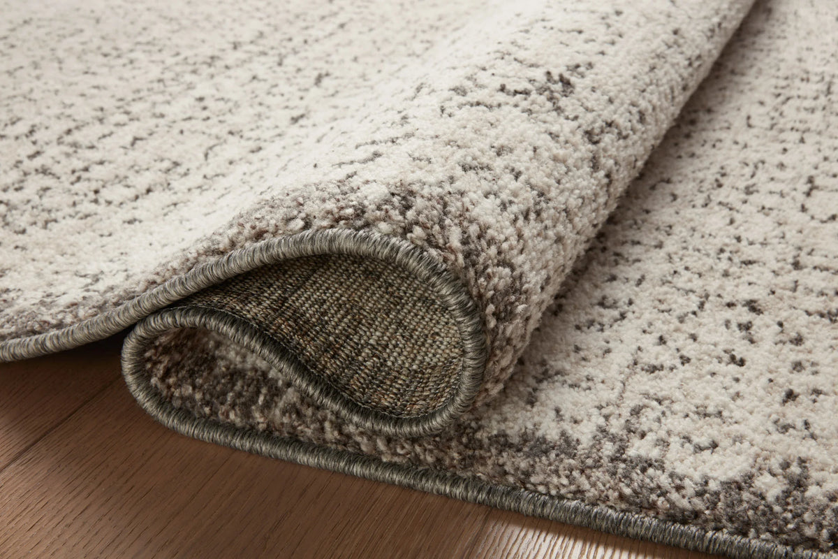 Ivory and stone rug detail showing curled edge and textured woven border