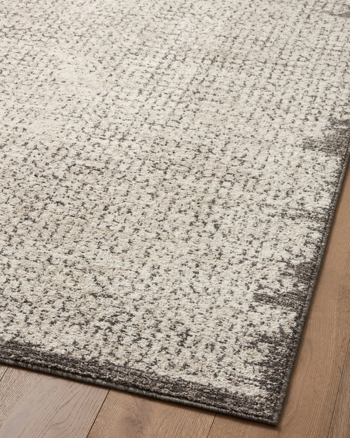 Ivory and stone accent rug with dense speckled texture and dark border trim