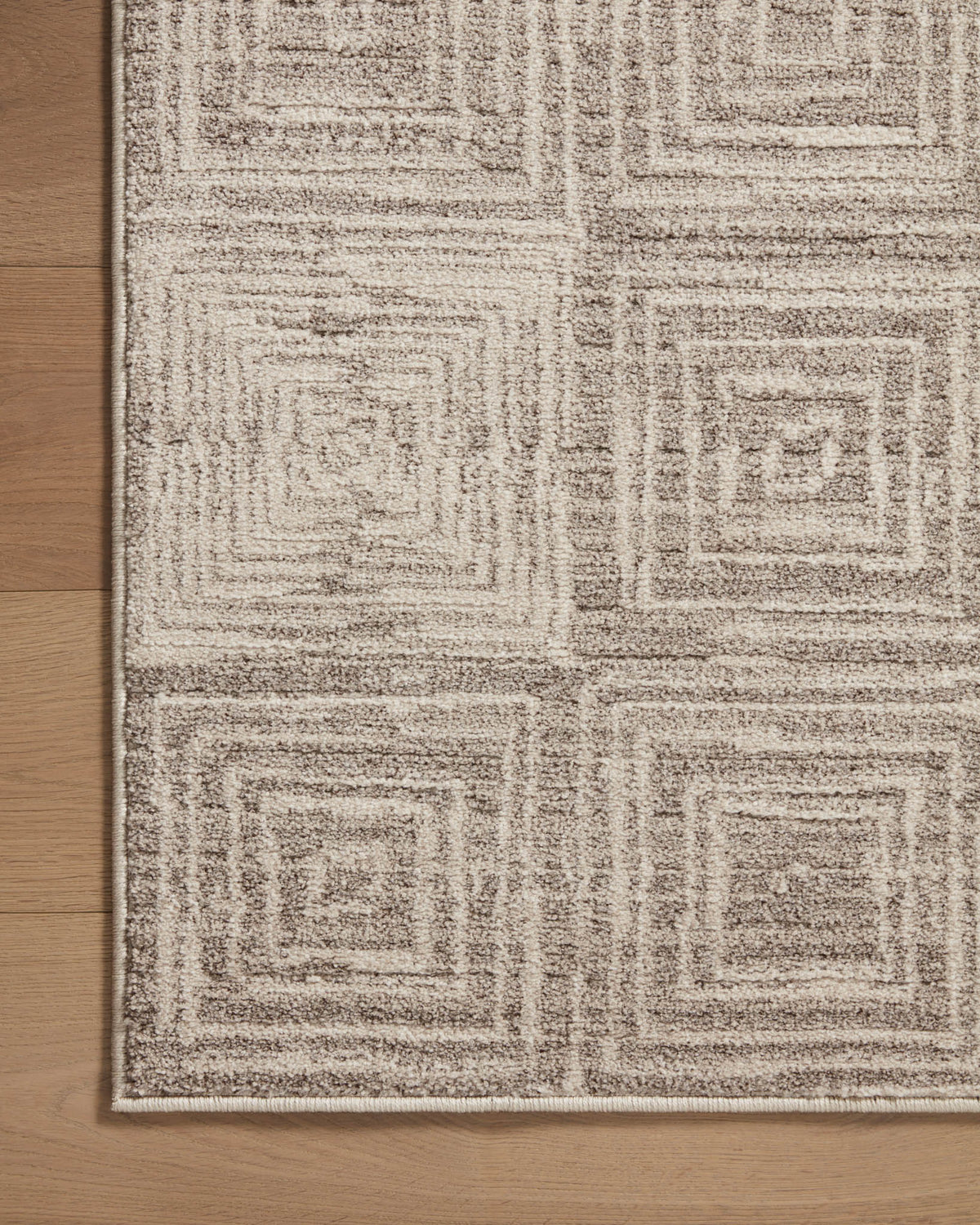 Beige and gray geometric area rug corner on wood floor, flat woven texture