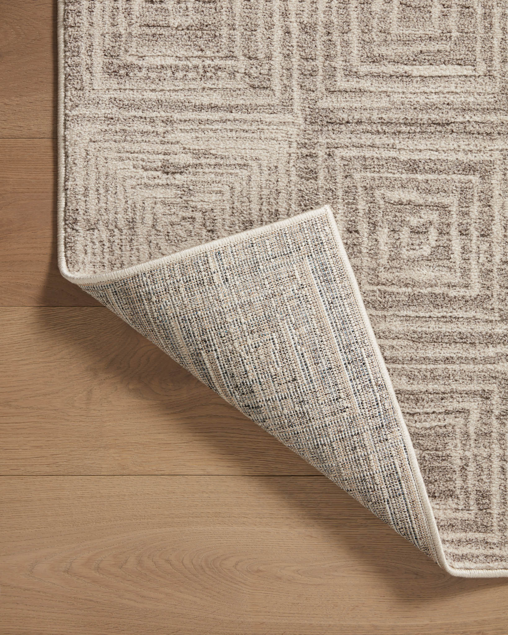 Beige and gray geometric runner rug showing flipped corner and bound border