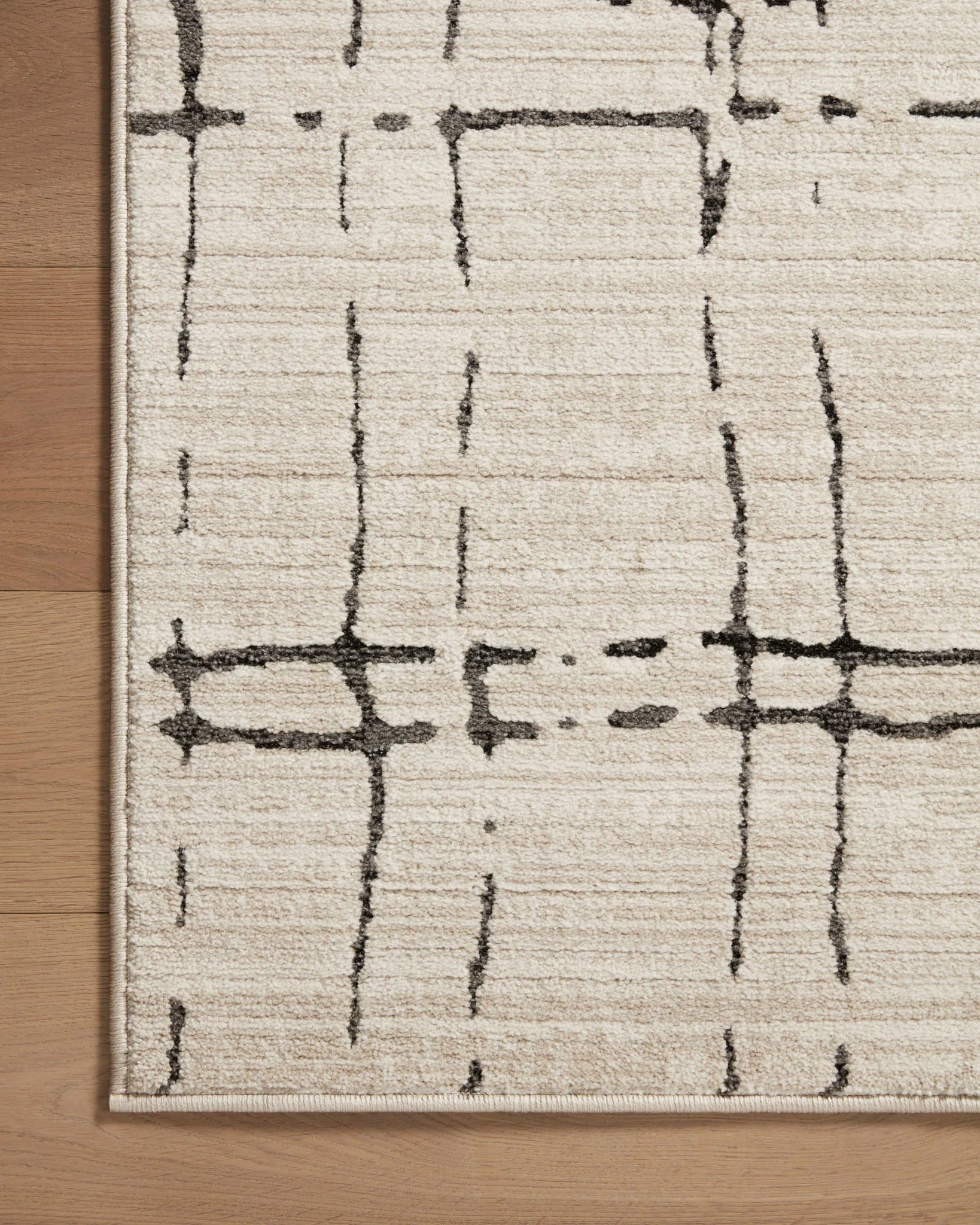 Sand rug panel with dark gray intersecting line pattern and flat woven border