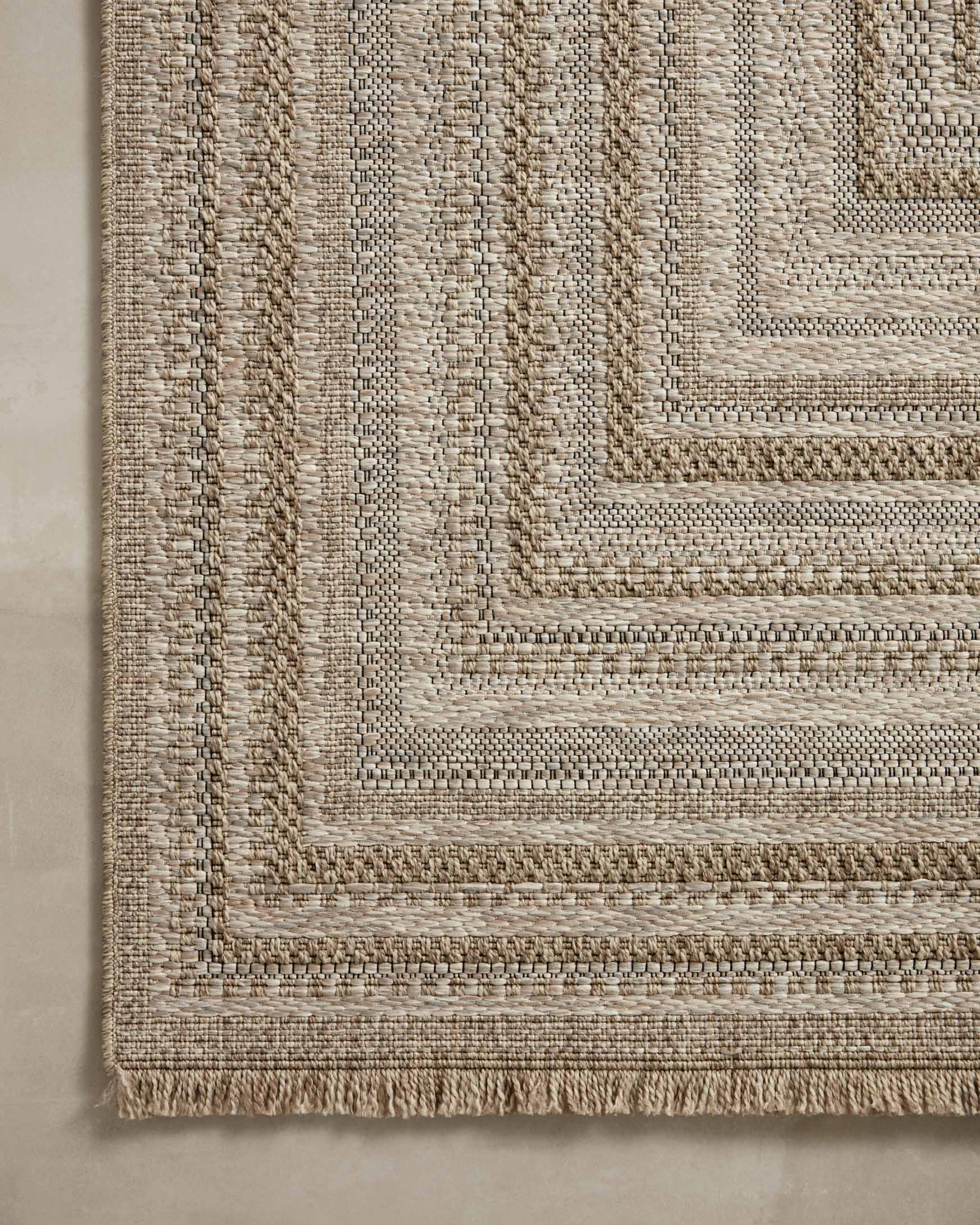 Natural woven rug close-up with fine striped threads and geometric border detail